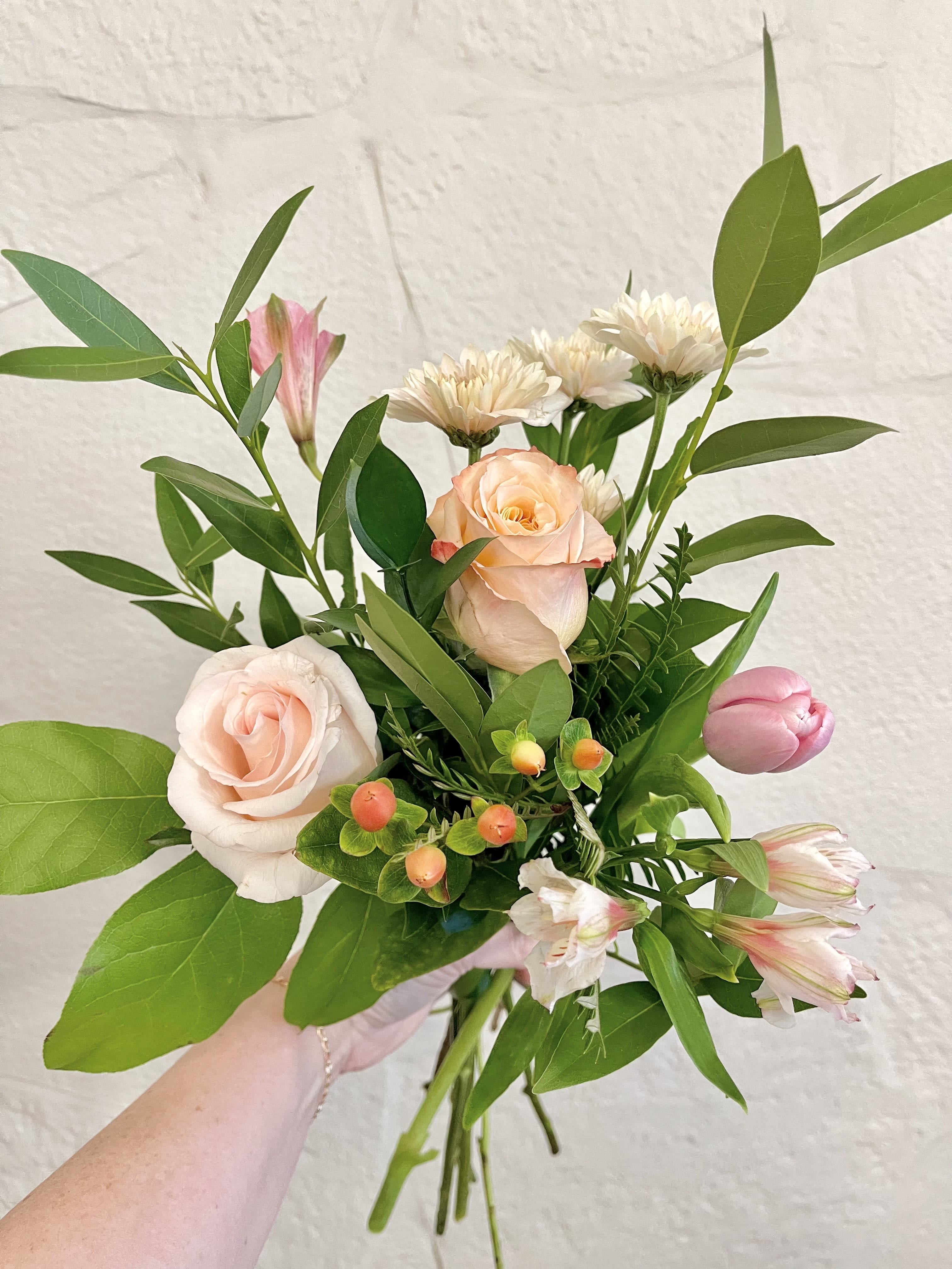 Sweetheart Mix Hand-tied Bouquet - Five stems of pink, peach, and pastel blooms with greenery and filler, wrapped in gold paper and tied with a bow.  (Water source provided).  Flower varieties may vary while maintaining the same color palette and overall style.