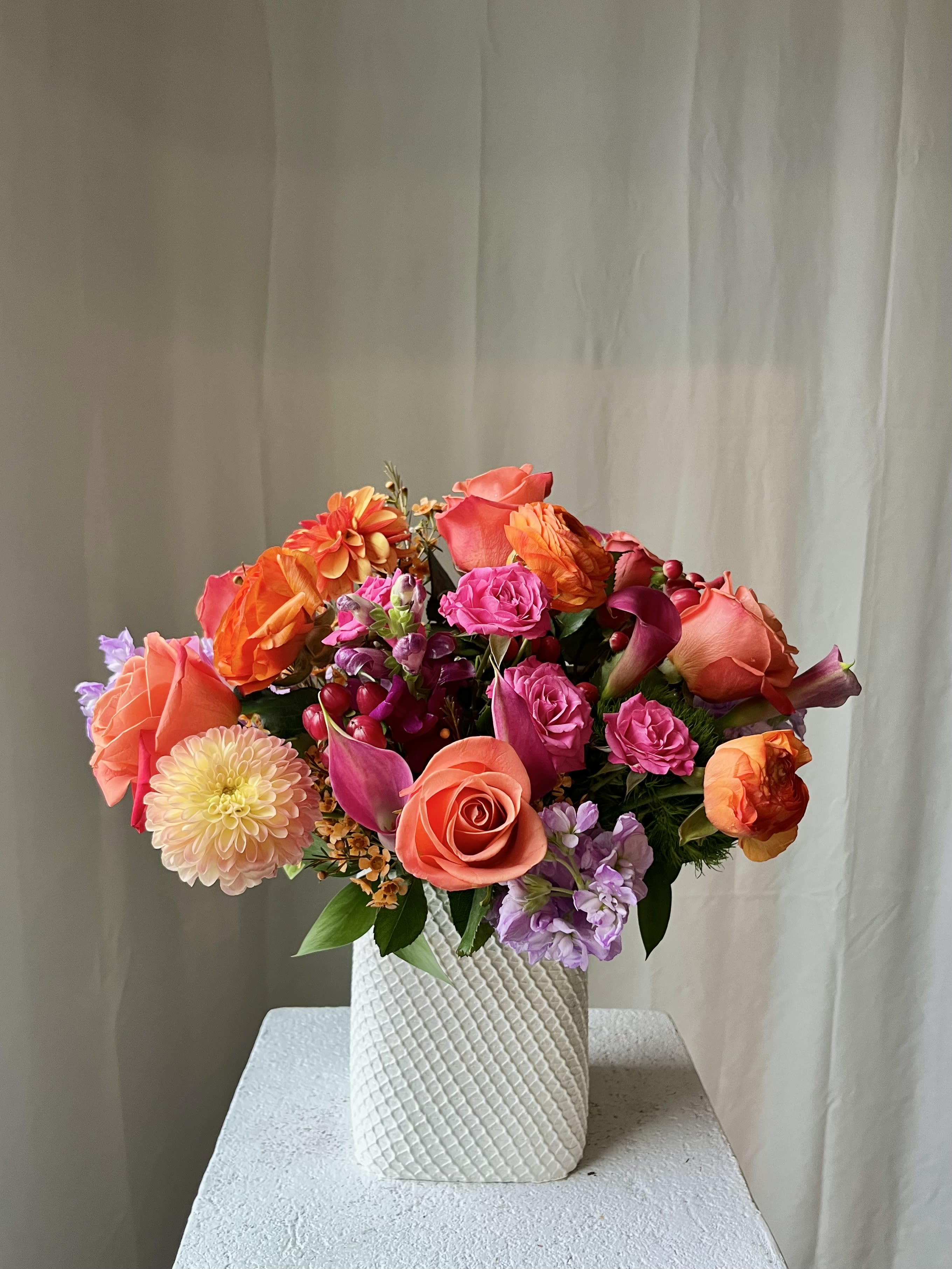 Good Vibrations - Brighten up the mood with this beautiful arrangement. Medium sized with a warm palette of oranges, pinks, and a hint of purple, it will be sure to make anyones day!  These are locally sourced flowers. Flowers used depend on availability, but our designers will preserve the spirit and the shape of the design.  While some of the content may vary, this arrangement will include pink and orange flowers.  