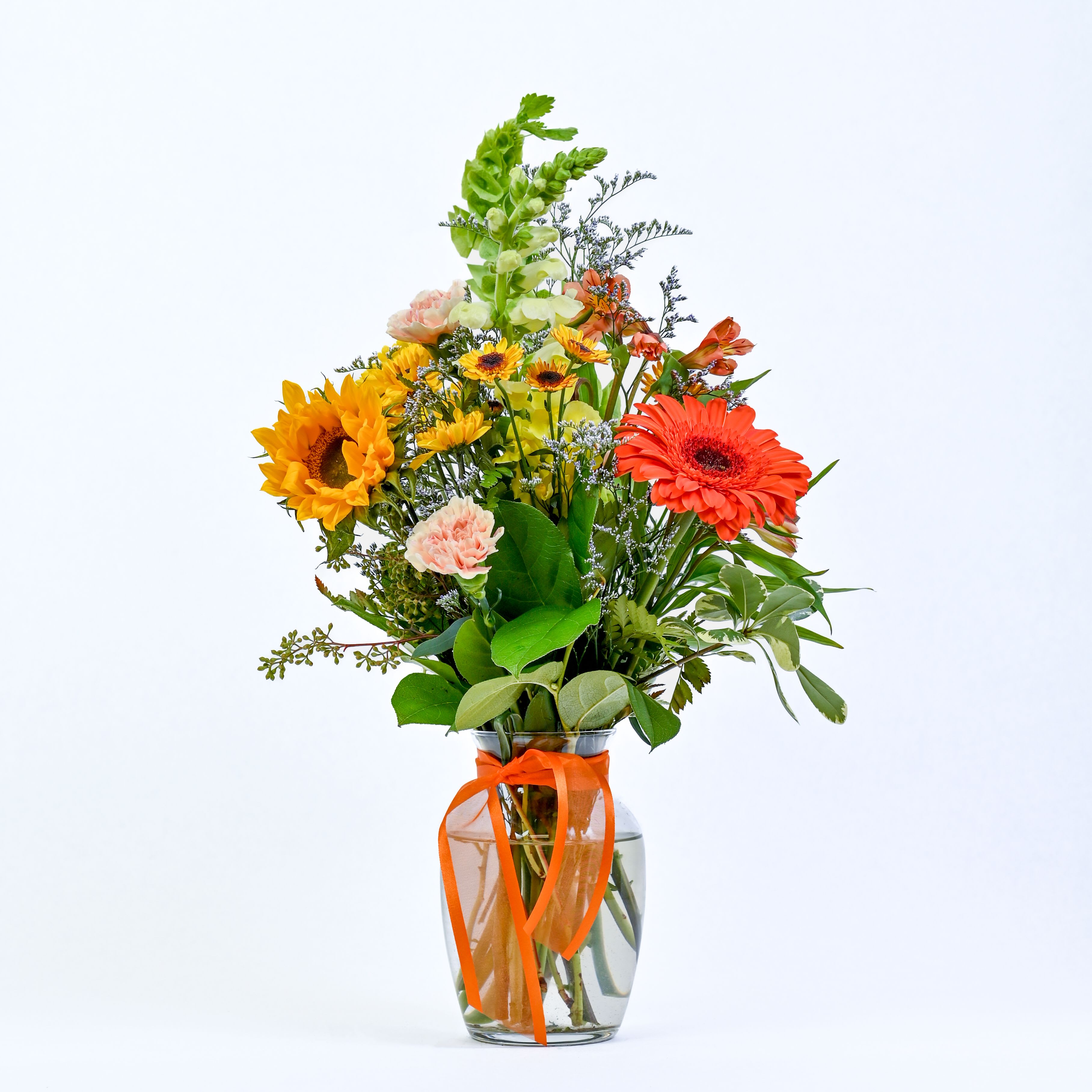 Bright Beginnings - Vibrant bouquet with bright sunflowers, playful gerbera, meet delicate pixies, carnations, and snapdragons, with airy misty, alstroemeria, bells, pittosporum, and seeded eucalyptus for texture and charm.