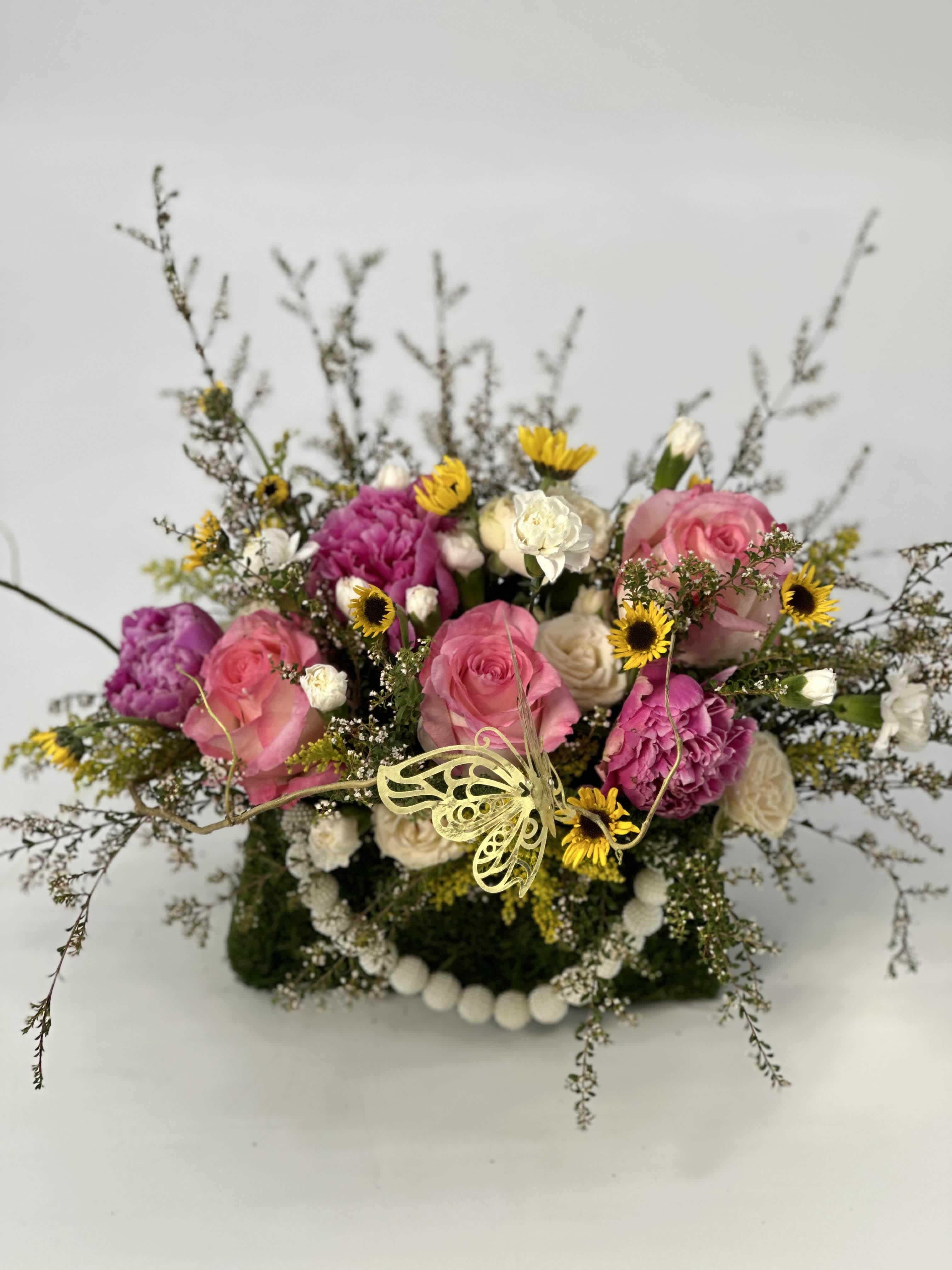 Whispering Garden - Refined ,low -profile floral arrangement composed of blush and rose -toned layered with soft ivory accent and touched of warm ,golden yellow .Delicate airy greenery creates graceful movement, while a subtle gold butterfly details add and elevated ,culture finish.Elegant ,romantic ,and thoughtfully balanced, tis piece embodies ,quiet luxury and timeless sophistication.