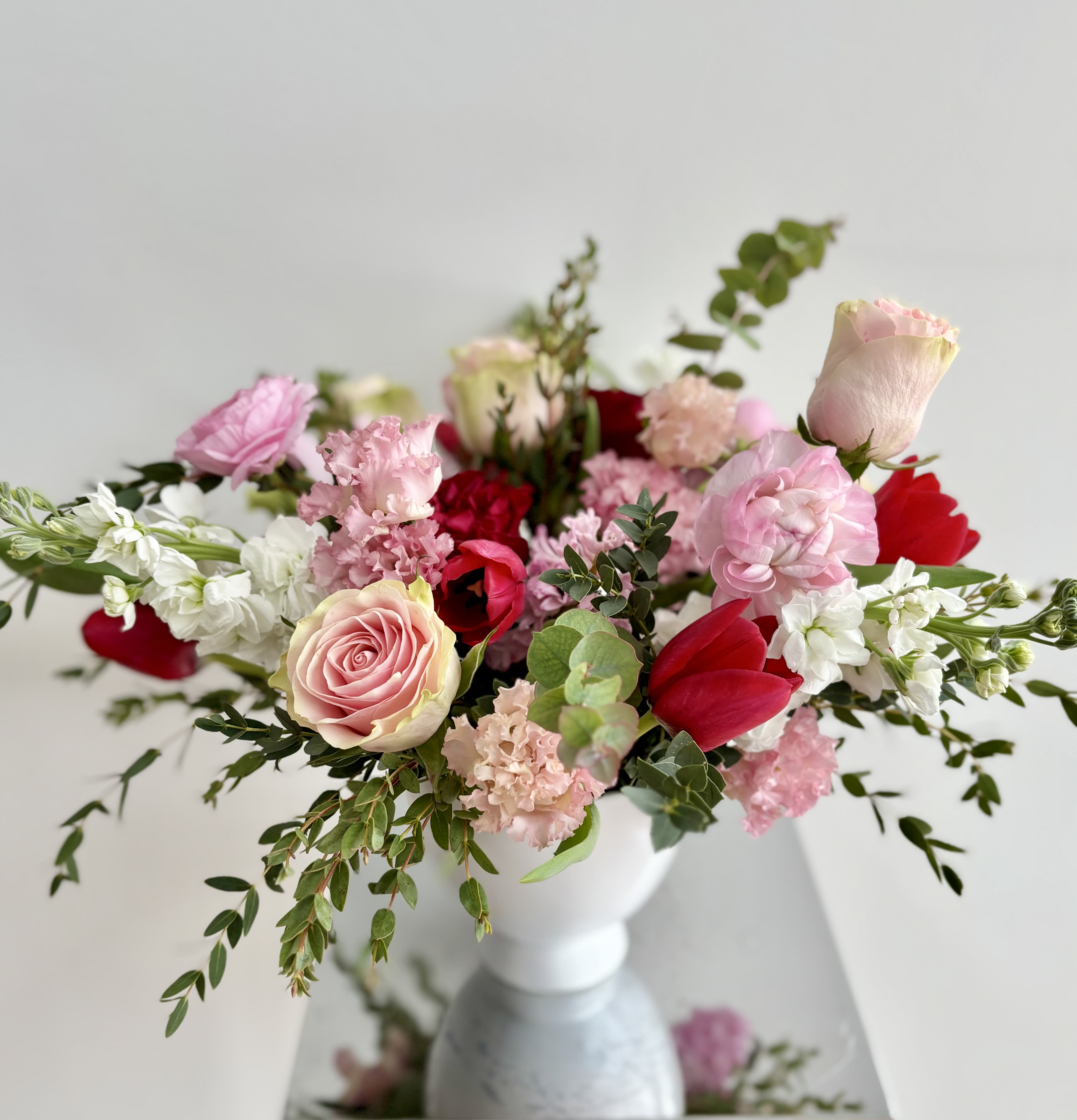 Perfect Valentine - A stunning arrangement with beautiful red, pink and white blooms in a white compote vase designed in a garden style. The selection of premium flowers may vary but rest assured that you will get a gorgeous bouquet of roses, ranunculus, lisianthus, stock, tulips, and more.