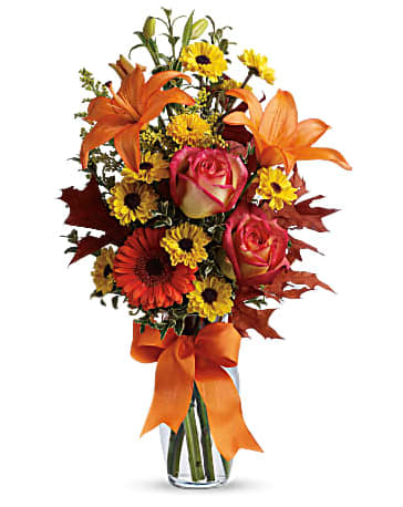 Burst of Autumn - A burst of beauteous blooms in autumn shades of orange and yellow is mixed with a handful of oak leaves, then delivered in a clear glass vase adorned with a bright satin ribbon. A splendid gift for birthdays or any fall occasion. A mix of fresh flowers such as Asiatic lilies, Viking spray chrysanthemums, roses and a miniature gerbera - in shades of orange and yellow - is arranged with preserved oak leaves in a clear glass vase adorned with an orange satin ribbon. Orientation: All-Around