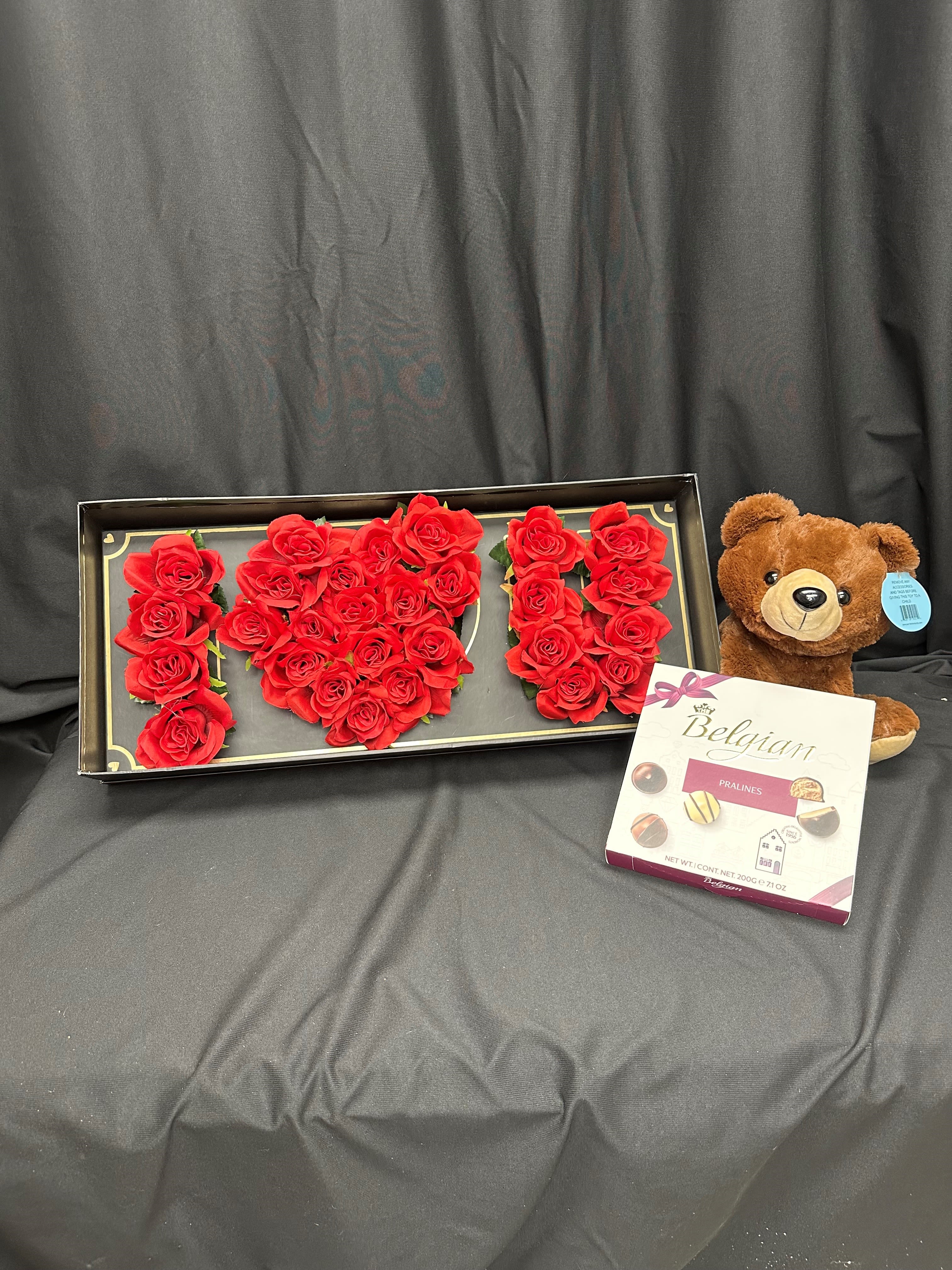 Love You Bundle - This elegant gift set features a stunning arrangement of fresh red roses beautifully shaped into the words "I Love You," making it the perfect expression of love and appreciation. Accompanied by a cuddly plush teddy bear and a delightful box of Belgian pralines, this thoughtful combination is sure to warm anyone's heart. Whether for Valentine's Day, a birthday, or just to show you care, this gift set creates a memorable and heartfelt surprise.