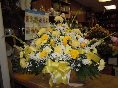 TB41 Traditional Basket - A mixture of white and yellow daisies, yellow carnations, yellow roses, yellow fuji mums, white snap dragons, yellow gladiolas, baby's breath, greens and lavender bow  Banner - $15.00 + extra  Substitutions may apply due to flower availability