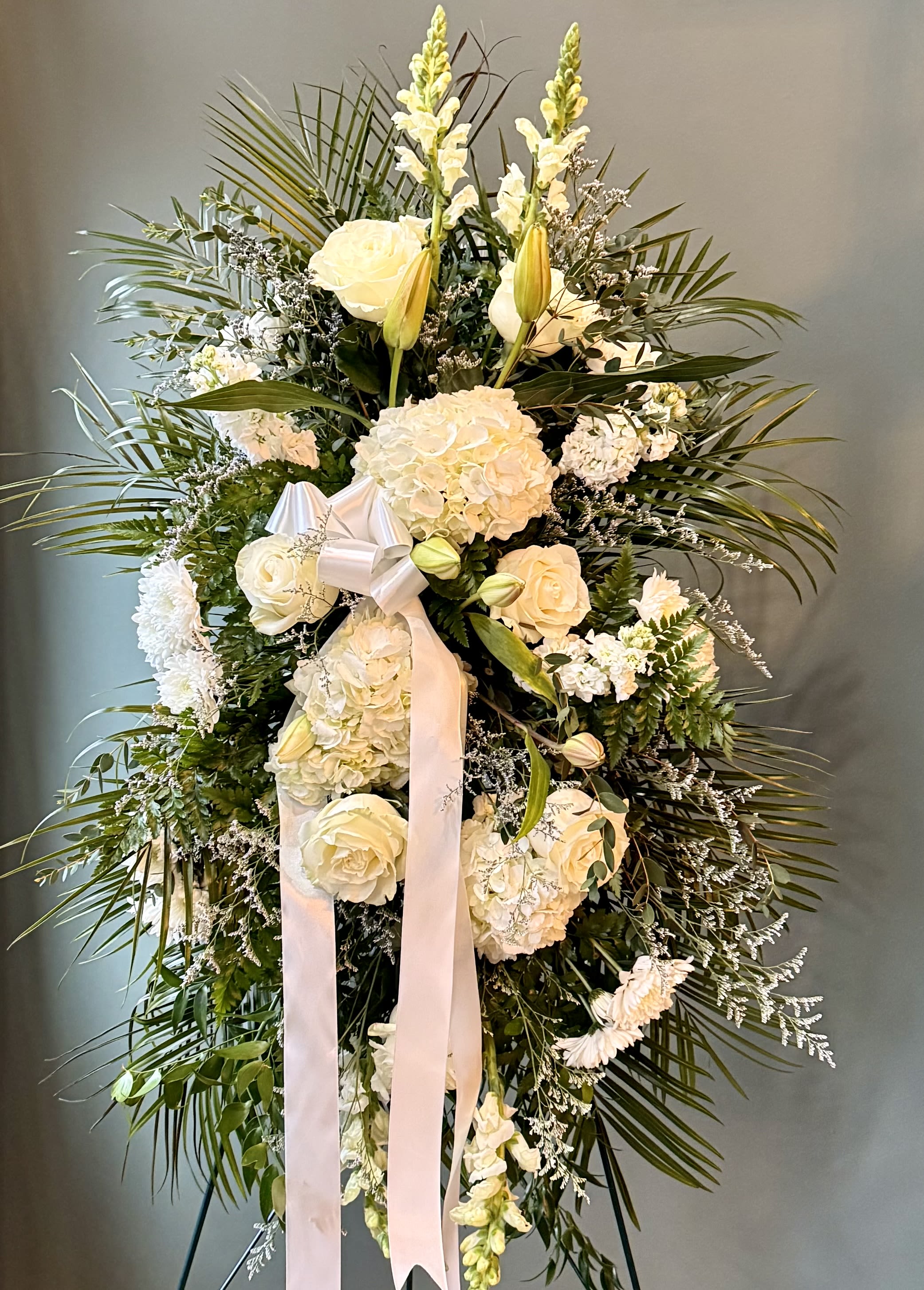 True Sympathy by BloomNation™ - An all white tribute, this funeral spray is pure and tranquil. Featuring a variety of white flowers and green palms this elegant funeral spray brings a feeling of peace to it's surroundings 