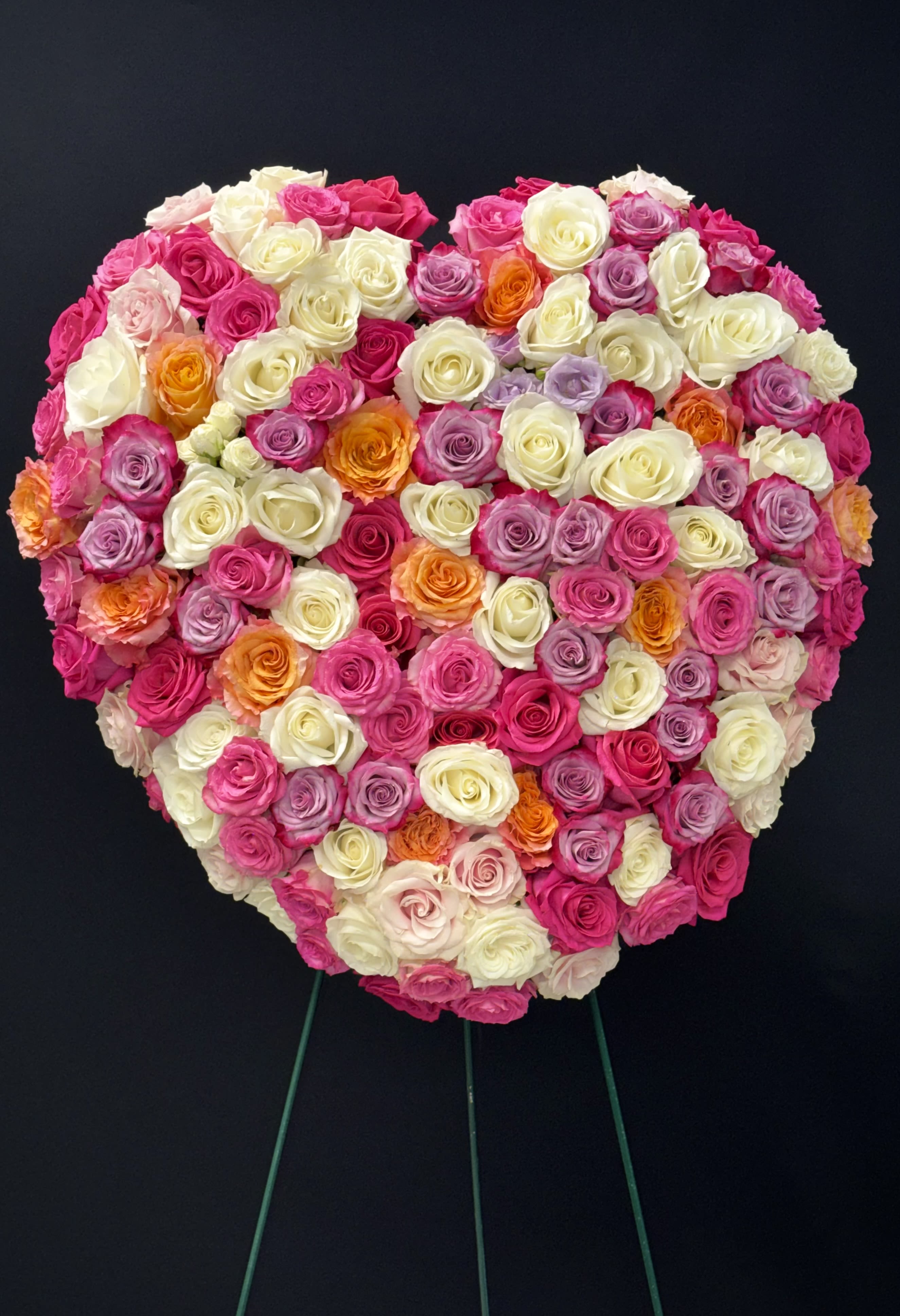  Loving Heart Spray - The fragrant pink, white, and lavender roses of this beautiful standing spray – created in the shape of a heart – will express your deepest love and devotion to all in attendance.