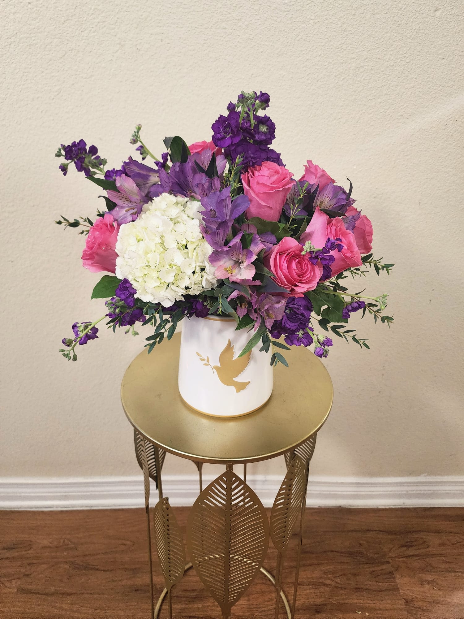 Graciella - A graceful confection designed to speak when words fall short. Soft pink roses, calming purples, and pure white blooms come together to express peace, love, and heartfelt remembrance. Elegant, comforting, and timeless while offering a gentle message of support and serenity during moments of loss.