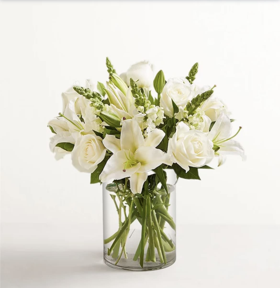 White Classic - All-around arrangement with all white flowers, designed in a glass cylinder vase. Standard cylinder vase 5", Deluxe and Premium cylinder vase 6"