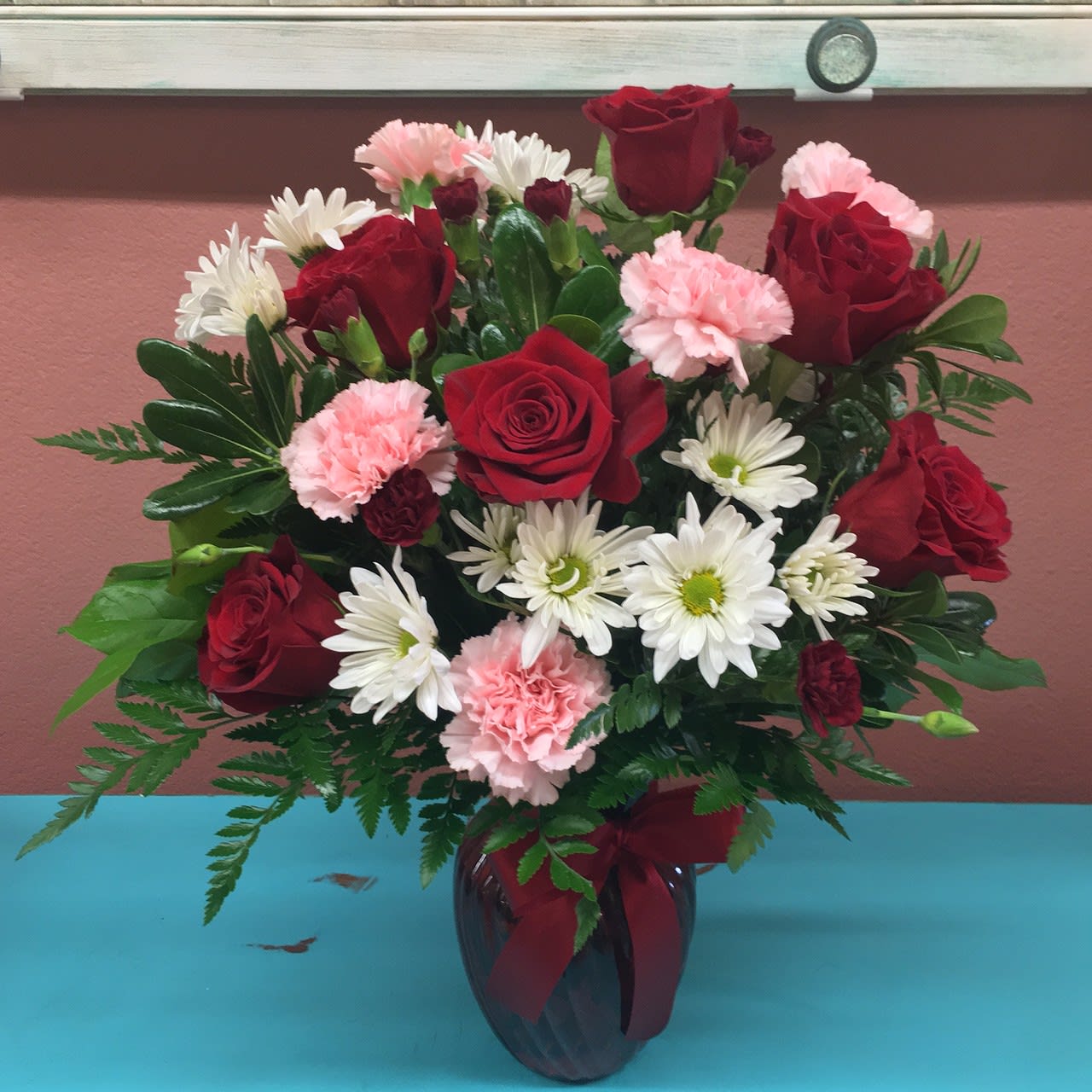 Love and Kisses - This hand crafted arrangement comes with a half dozen Red roses, pink Carnations and white chrysanthemums. Vase may vary. 