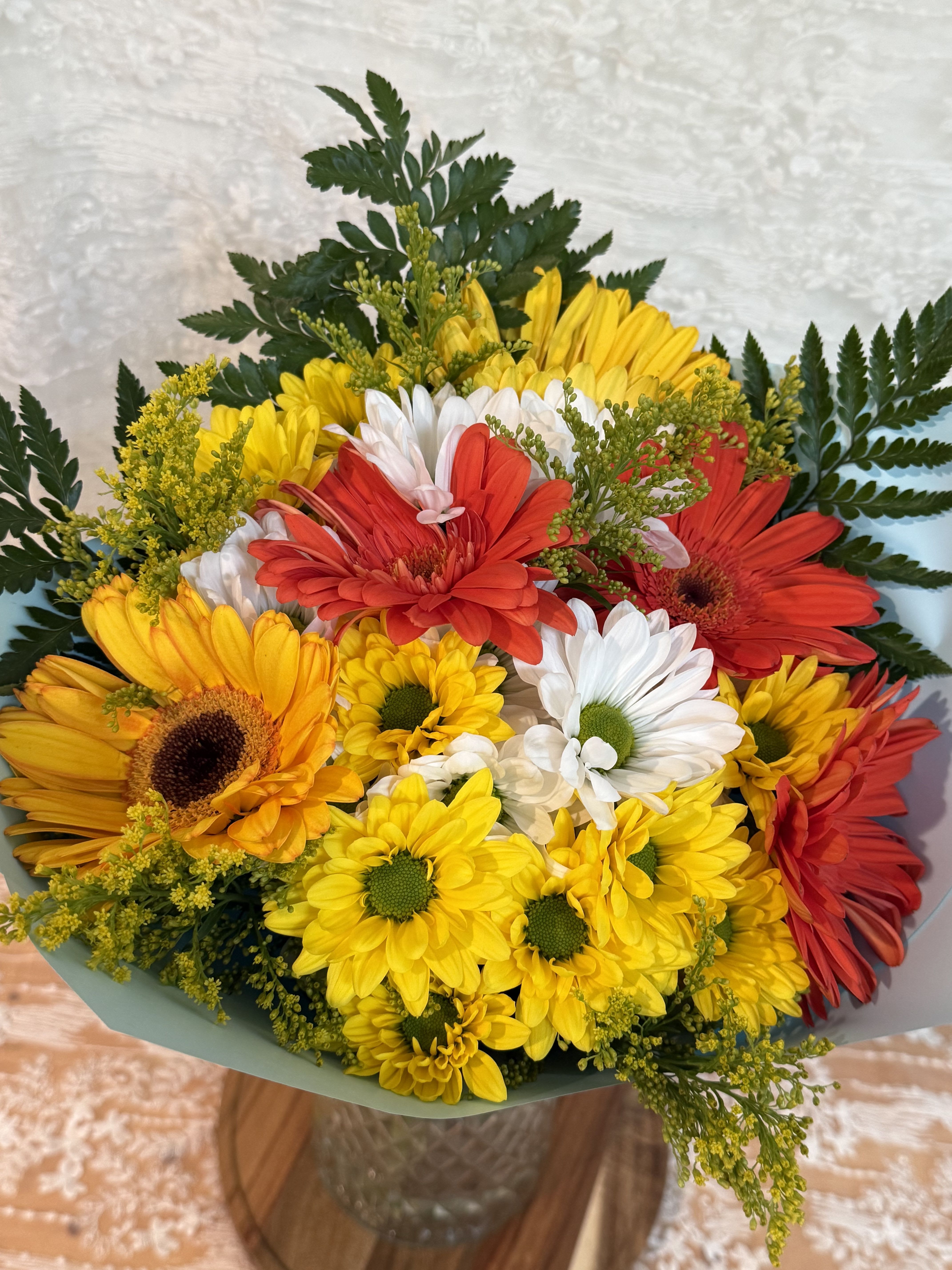 Daisy Sunrise  - Daisy wrapped bouquet with daisy ribbon   If a particular flower, is unavailable, an item of similar quality and value will be substituted.