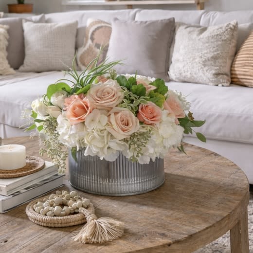 Peach Perfect  - Peach Perfect is a beautifully balanced floral arrangement designed to bring warmth, softness, and effortless California style into any home. Featuring premium peach and blush roses, lush white hydrangea, and fresh seasonal greenery, this arrangement is artfully styled in a modern galvanized metal cylinder for a look that feels both relaxed and refined.  Inspired by sun-filled Los Angeles interiors and boho-chic living, Peach Perfect is the ideal statement piece for a living room coffee table, dining table, or entryway. Its gentle peach tones and creamy neutrals create an inviting atmosphere that complements modern farmhouse, bohemian, coastal, and cottage-style homes.  Perfect for birthdays, anniversaries, housewarmings, thank-you gifts, or simply elevating everyday living, Peach Perfect delivers timeless beauty with a fresh, modern touch.   Arrangement Details  Premium peach &amp; blush roses  White hydrangea  Seasonal greenery &amp; textural accents  Designed in a modern galvanized metal container  Low, lush profile ideal for coffee tables  Each arrangement is handcrafted with care, ensuring no two are exactly alike—making every Peach Perfect truly one of a kind. Arrangement is approximately 12WX7H 
