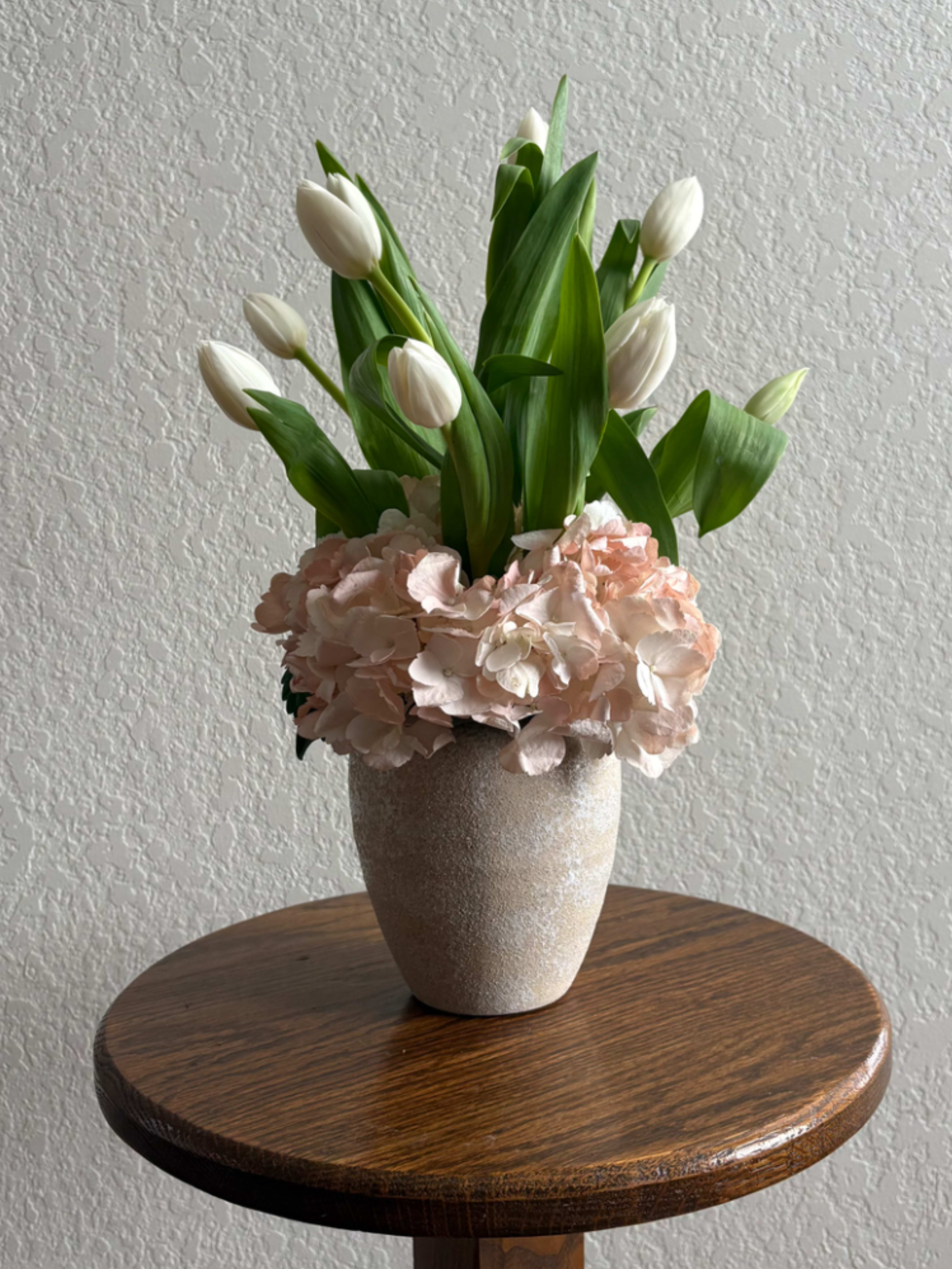 Cloud Nine Tulips - Cloud Nine is a breath of fresh air wrapped in petals. Featuring delicate white tulips nestled among lush blush-pink hydrangea, this arrangement is designed in a creamy ceramic vase for a look that’s effortlessly elegant and endlessly calming. Light, airy, and full of quiet romance, Cloud Nine is perfect for Valentine’s Day when love is in the air—or any day you want to make someone feel cherished.