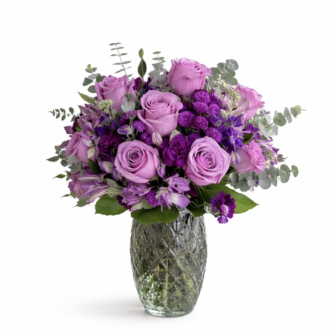 Sweet Purple Dreams - A graceful blend of lavender and blush roses, deep purple blooms, and soft alstroemeria, accented with fresh eucalyptus and lush greenery. Arranged in a textured green glass vase, this bouquet delivers charm, beauty, and timeless elegance for any occasion.