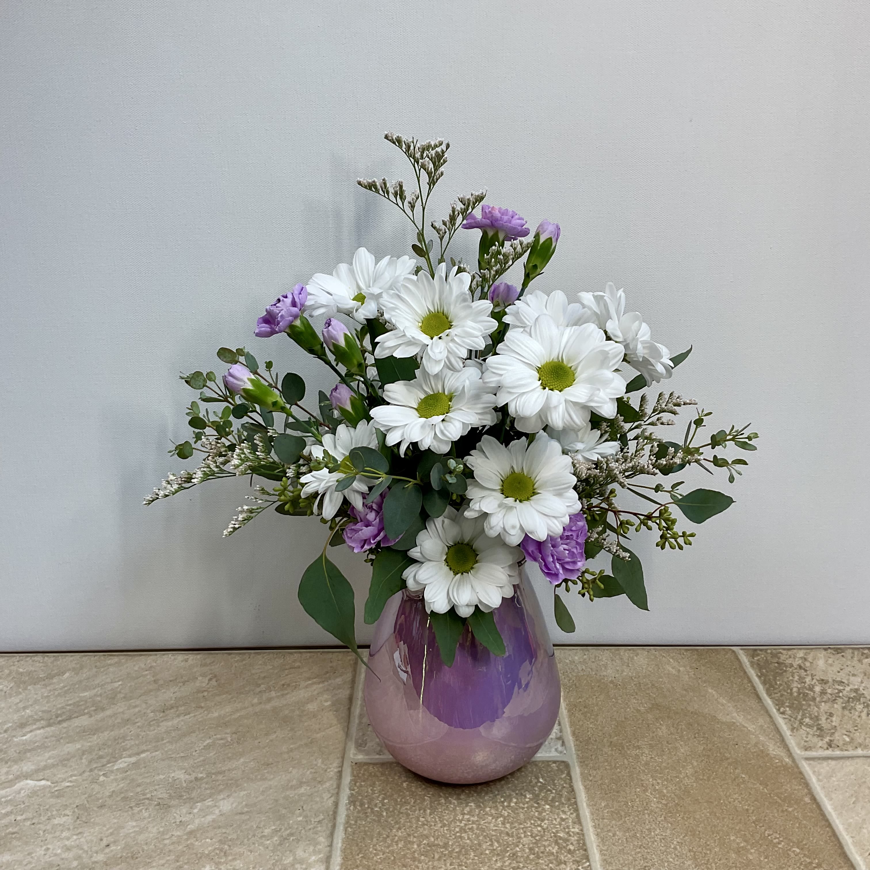 Fresh as a Daisy - A delightful bouquet of fresh white daisies, limon and lavender mini carnations arranged in a pretty iridescent teardrop glass vase. It measures 11” wide x 15” tall.
