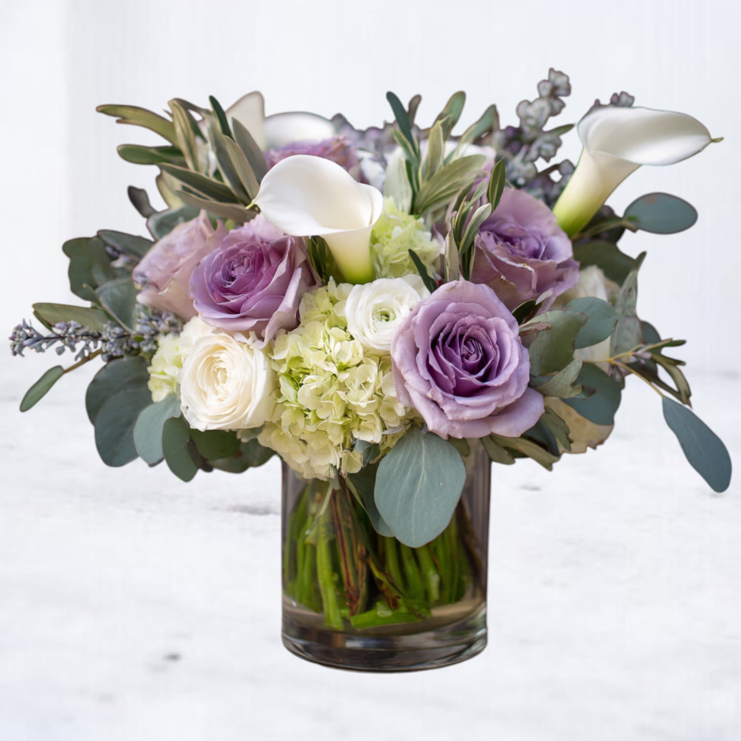 Twilight Reverie - Graceful and refined, our Twilight Reverie Bouquet blends rich plum calla lilies, soft lavender roses, and pure white lilies, crisp white carnations with lush greenery. The mix of dramatic jewel tones and delicate pastels creates a captivating design, perfect for birthdays, anniversaries, sympathy gestures, or simply to send beauty “just because.”  Available for same-day delivery in Magnolia, The Woodlands, Spring, and Montgomery, TX, this bouquet brings elegance and comfort to any space with premium seasonal blooms.