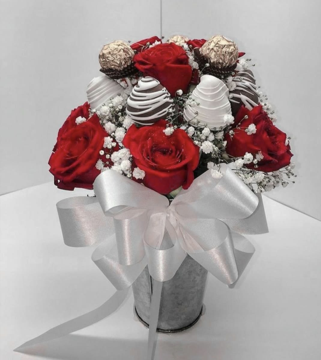The Classic Romance - Celebrate love in its purest form. This stunning arrangement features a curated selection of premium red roses, known for their deep color and velvety petals. Each set of roses is perfectly accented with a hand-tied designer bow, adding a touch of classic charm to the bold red base. It is the ultimate gesture of affection, designed to make a lasting impression this Valentine’s Day.