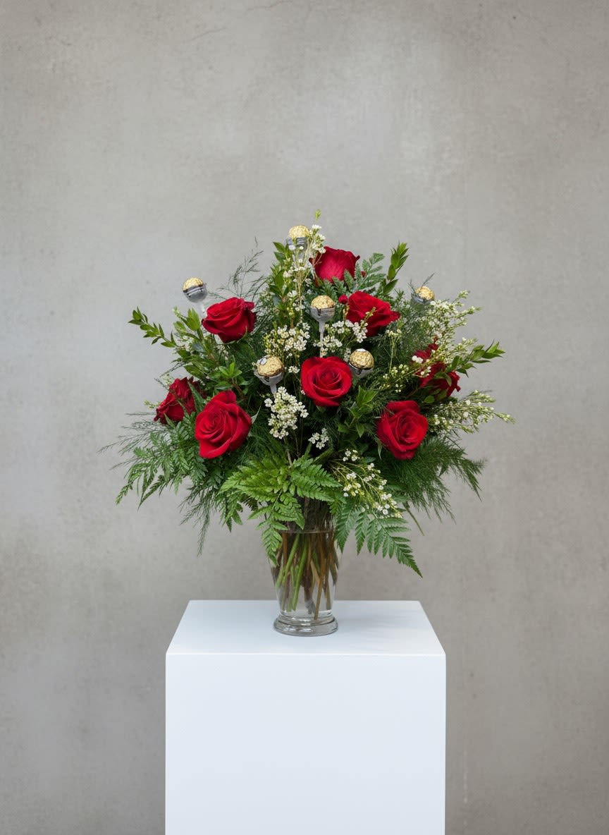 THE Double Dozen  - An unforgettable expression of love, The Double Dozen pairs timeless romance with modern elegance. This striking arrangement features one dozen classic roses alongside one dozen Ferrero tulips, beautifully accented with delicate wax flower and lush assorted greens. Designed in a clear vase, the combination creates depth, texture, and movement—blending bold passion with soft sophistication. Perfect for Valentine’s Day, this luxurious arrangement makes a grand statement that feels abundant, heartfelt, and truly special.