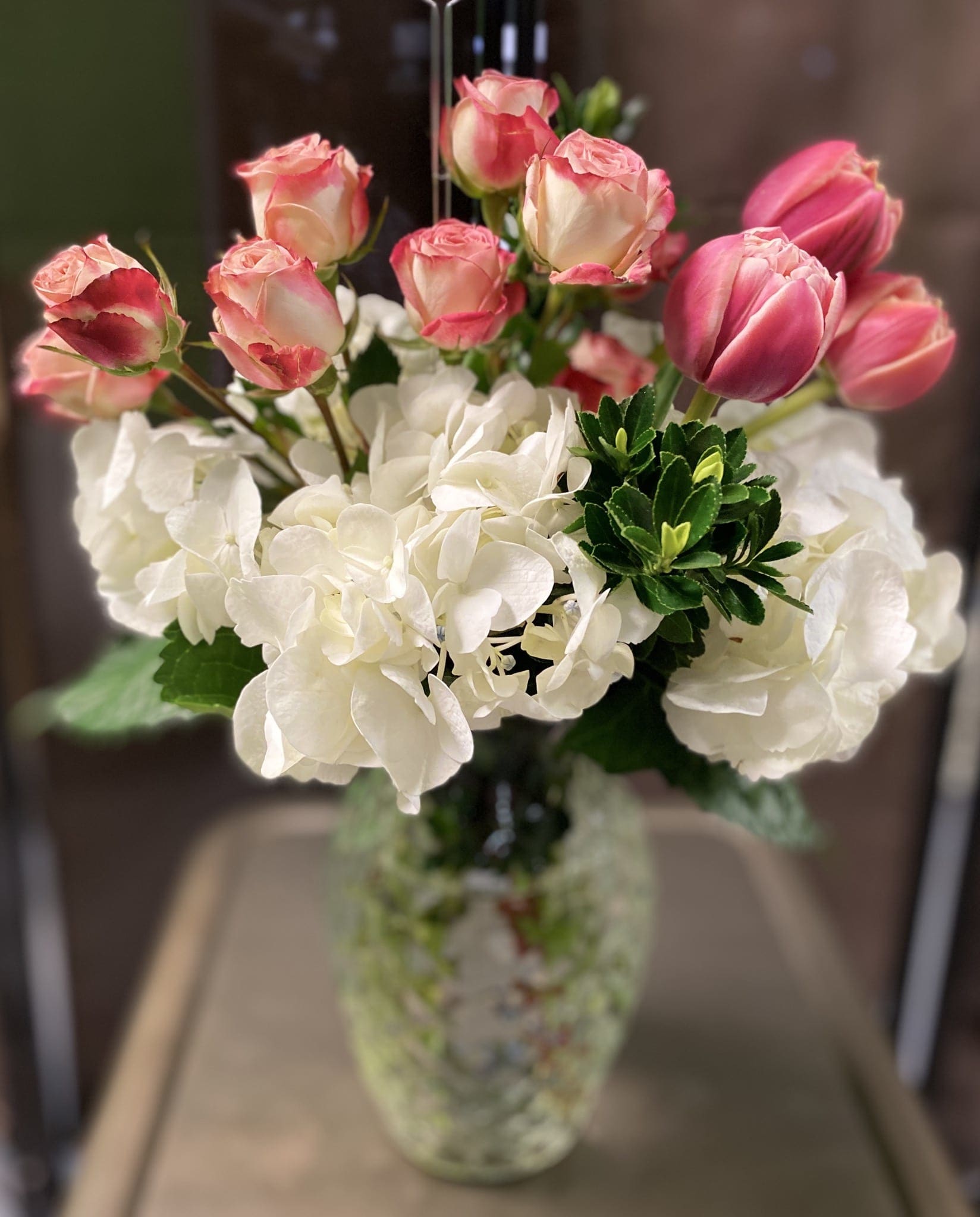 In The Clouds - Jumbo white hydrangea with a half dozen roses* and a trio of tulips* in a lovely vase. Perfect gift for hydrangea lovers!  *rose and tulip color may vary from red to shades of pink *Roses may be substituted for Tulips due to seasonality of tulips. 