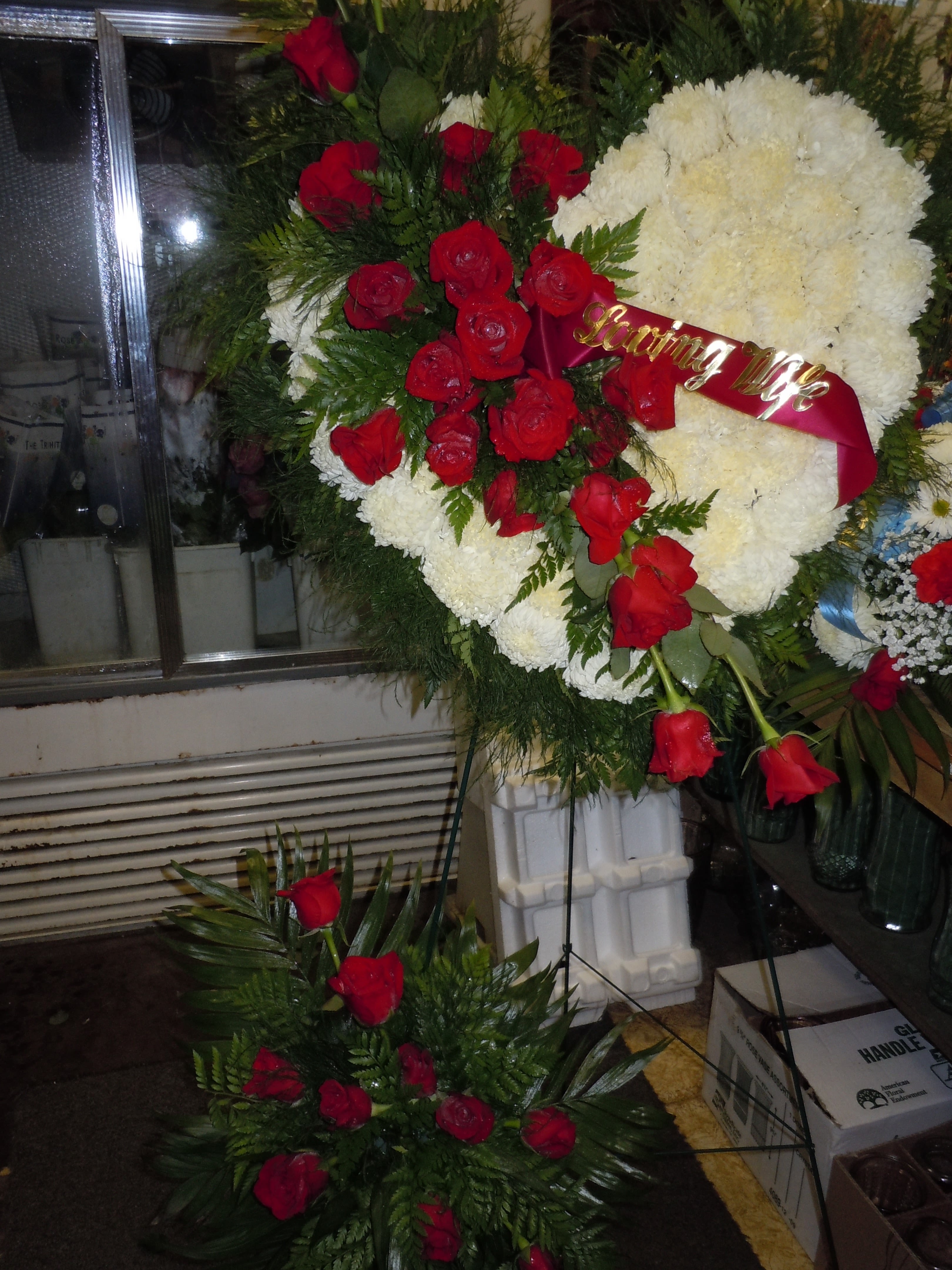 SP30 Standing Spray - A solid heart with a mixture of fuji mums, red roses, red roses at bottom,  and greens.   Banner - $15.00 + extra  Substitutions may apply due to flower availability