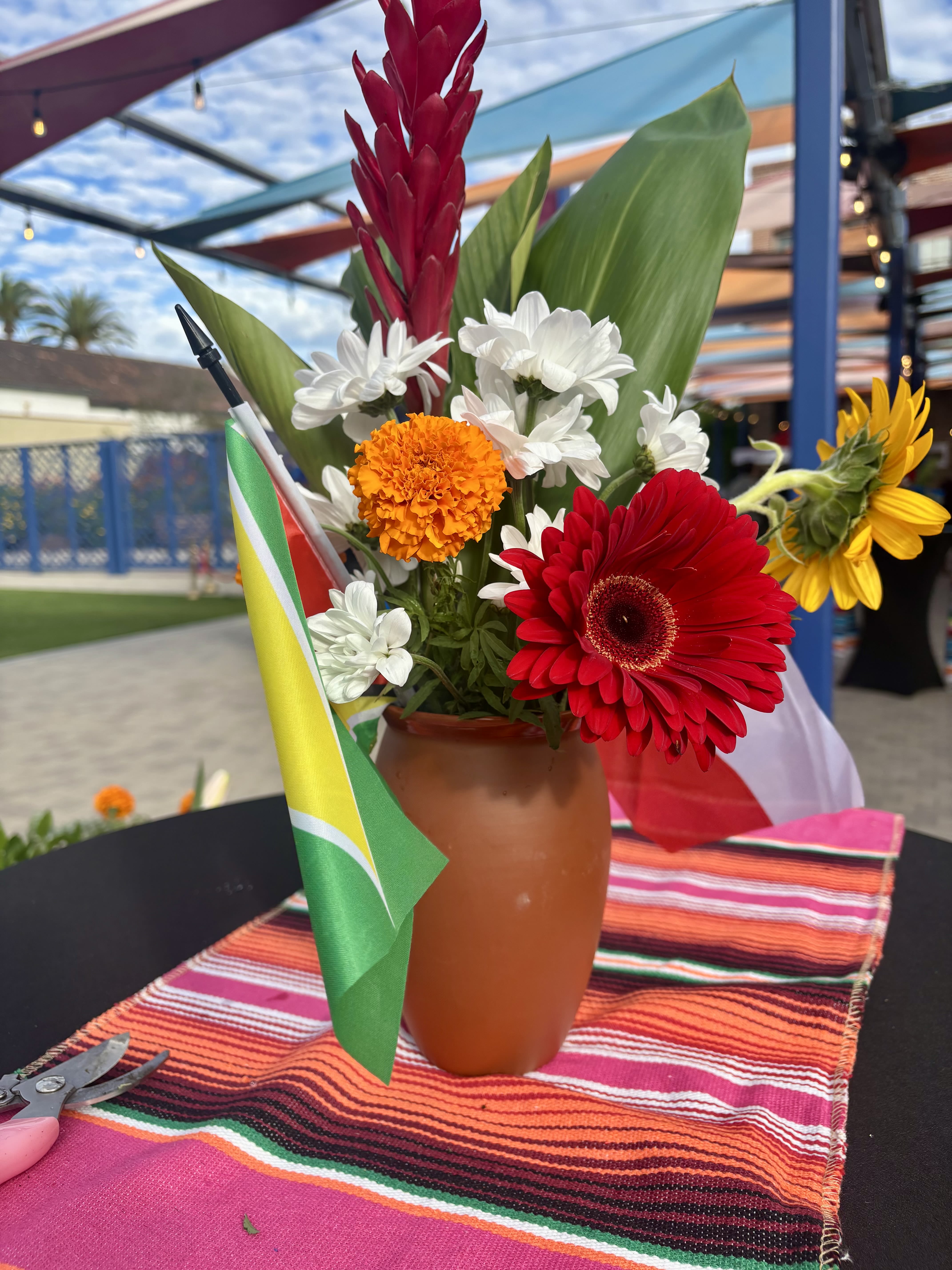 Bird of Paradise Bliss - Bird of Paradise Bliss is a bold yet refined floral statement designed for modern corporate environments and curated events. Featuring sculptural Bird of Paradise blooms accented with warm golden florals and balanced by soft neutral tones, this arrangement is grounded in a sleek terra-cotta vessel that adds a contemporary, design-forward finish.