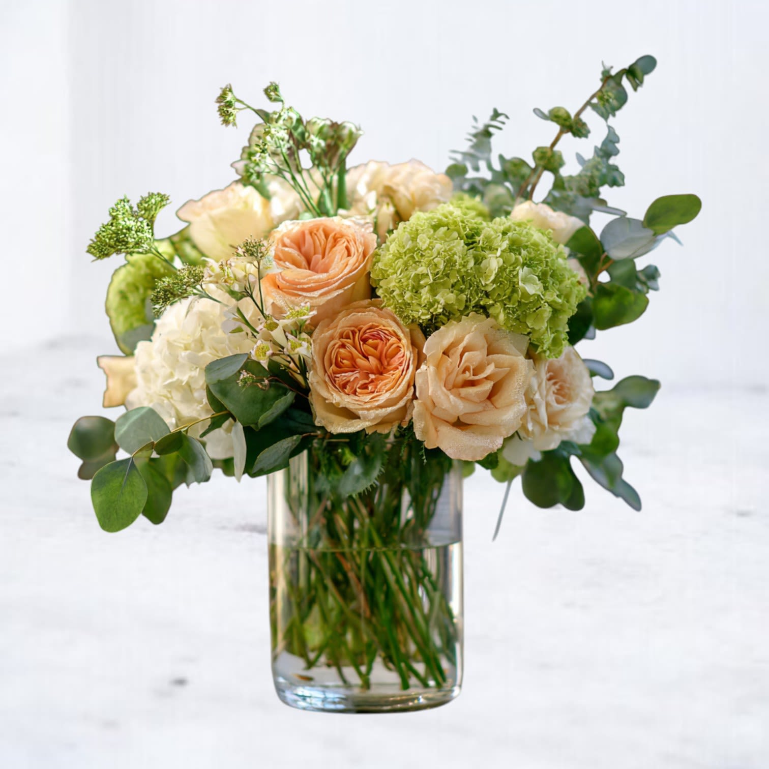 Peach Petals - Bring timeless elegance into any space with our Peach Petals, a graceful arrangement peach roses, soft hydrangeas and seasonal blooms. Designed in a clear glass vase, this bouquet blends modern minimalism with classic romance. Perfect for birthdays, anniversaries, or as a heartfelt sympathy gift, its soft pastel palette creates a calming presence and lasting impression. Handcrafted with care, this bouquet is ideal for delivery throughout Houston and surrounding areas, offering beauty and comfort for any occasion.