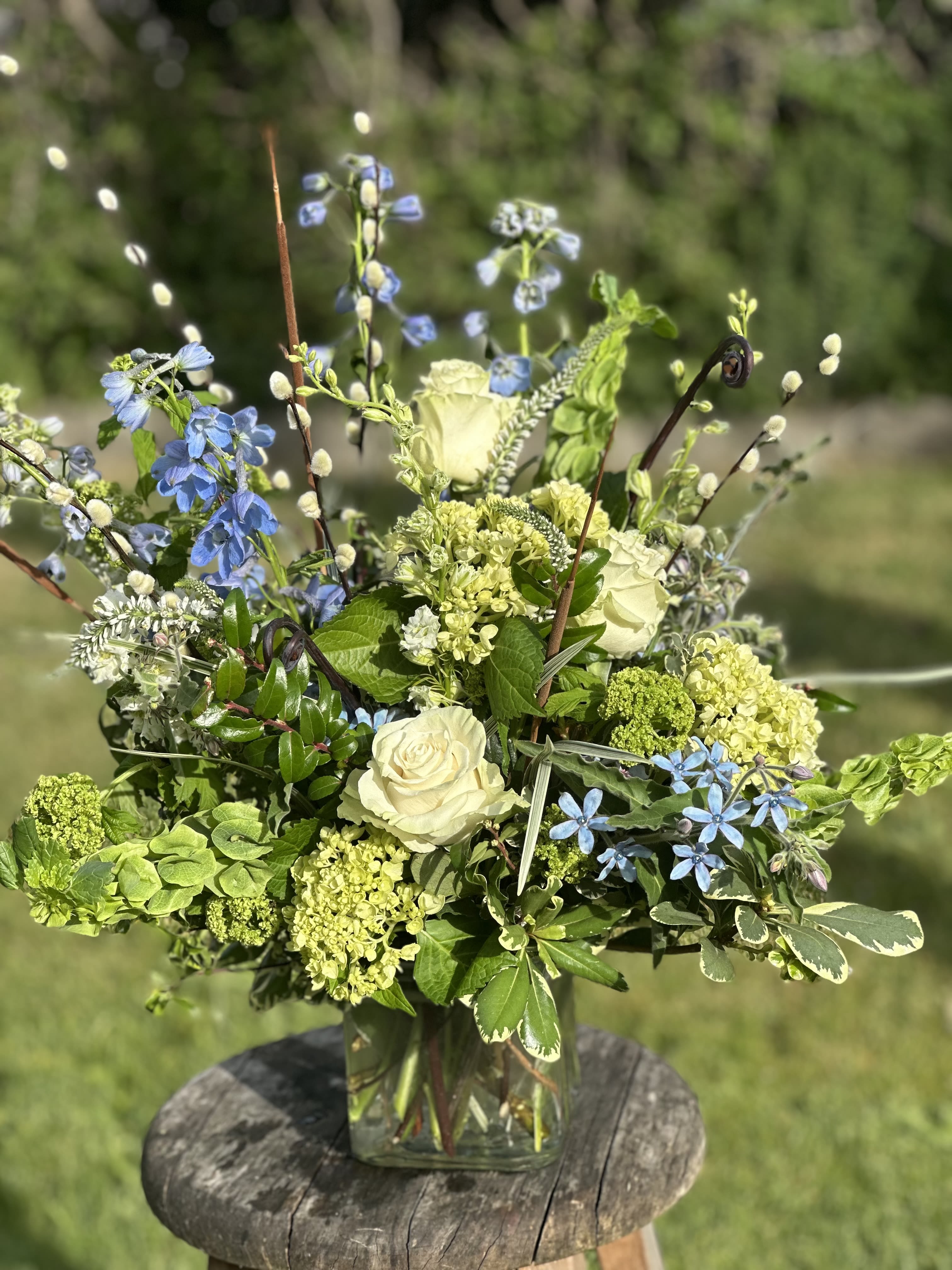 Salish Sea - An Ode to the Beautiful Olympic Peninsula. With a Mix of Blues, Greens, Local Greens, and Mossy Branches, this arrangement has the feel of the Pacific Northwest. *Please note that the photo is an example of the flowers chosen for this arrangement. It will remain in the same color palette and have the same feel as design shown.
