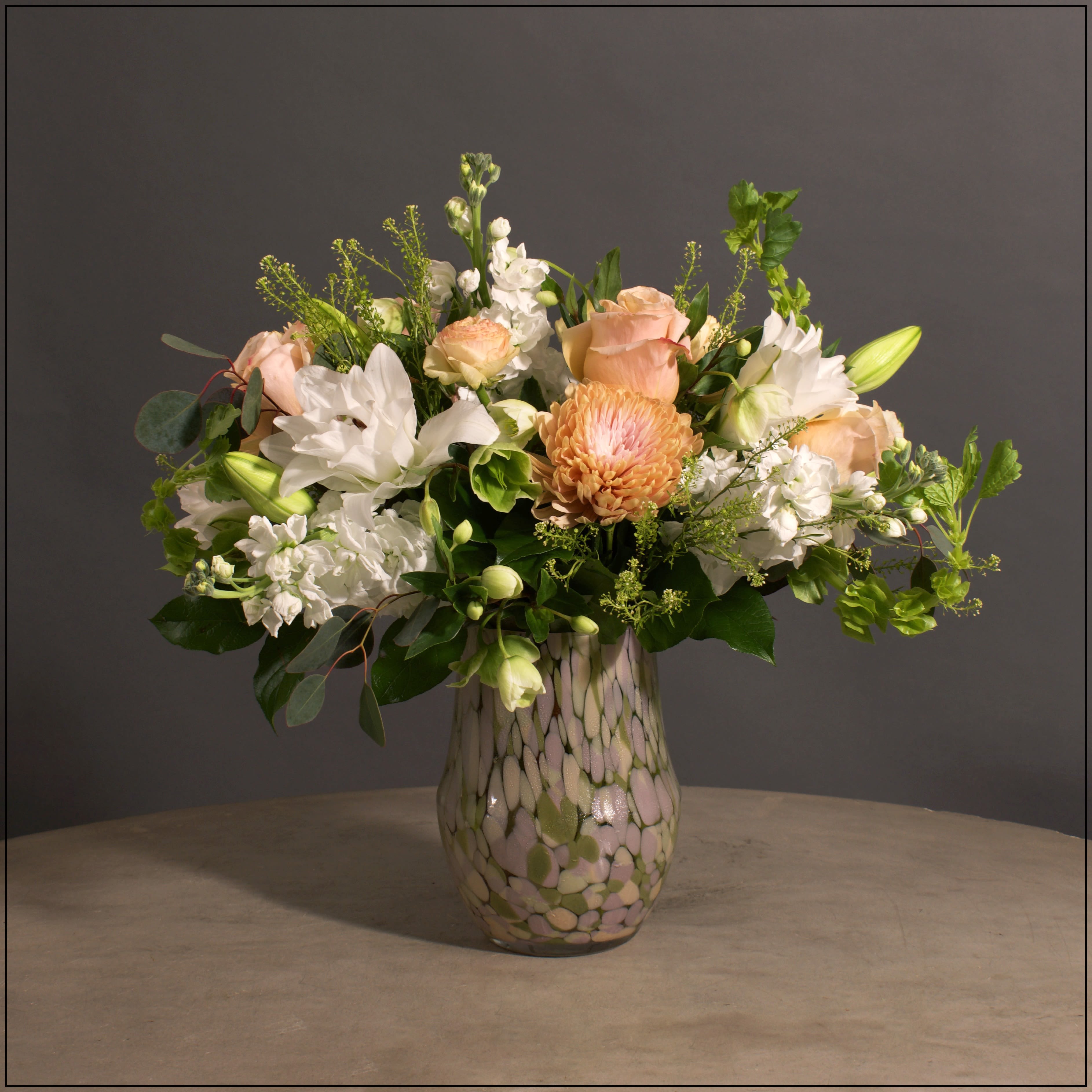 Art Glass Spring - Art Glass vase, a beautiful vase to keep, filled with Stock, Belles of Ireland, Cremones, Lilies, Roses, Heleborus, Roses, and Ranunculus. Approximate size 18" tall and 19" wide.