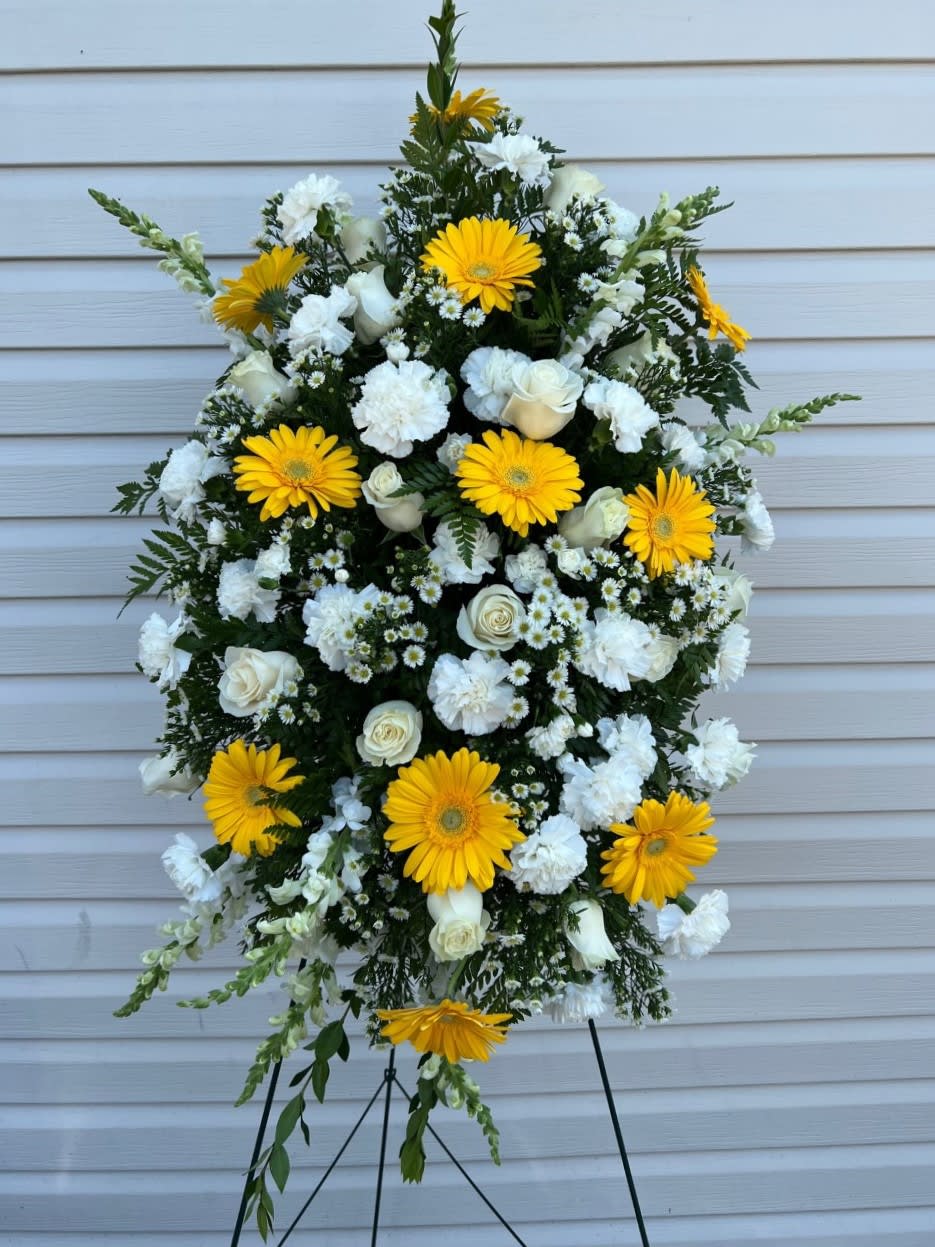 The Eternal Light Standing Spray - This elegant one-sided spray is composed of all white flowers. White roses spider chrysanthemums carnations snapdragons and Monte Casino are perfected by greenery in assorted shapes and textures.   FCS11-3795