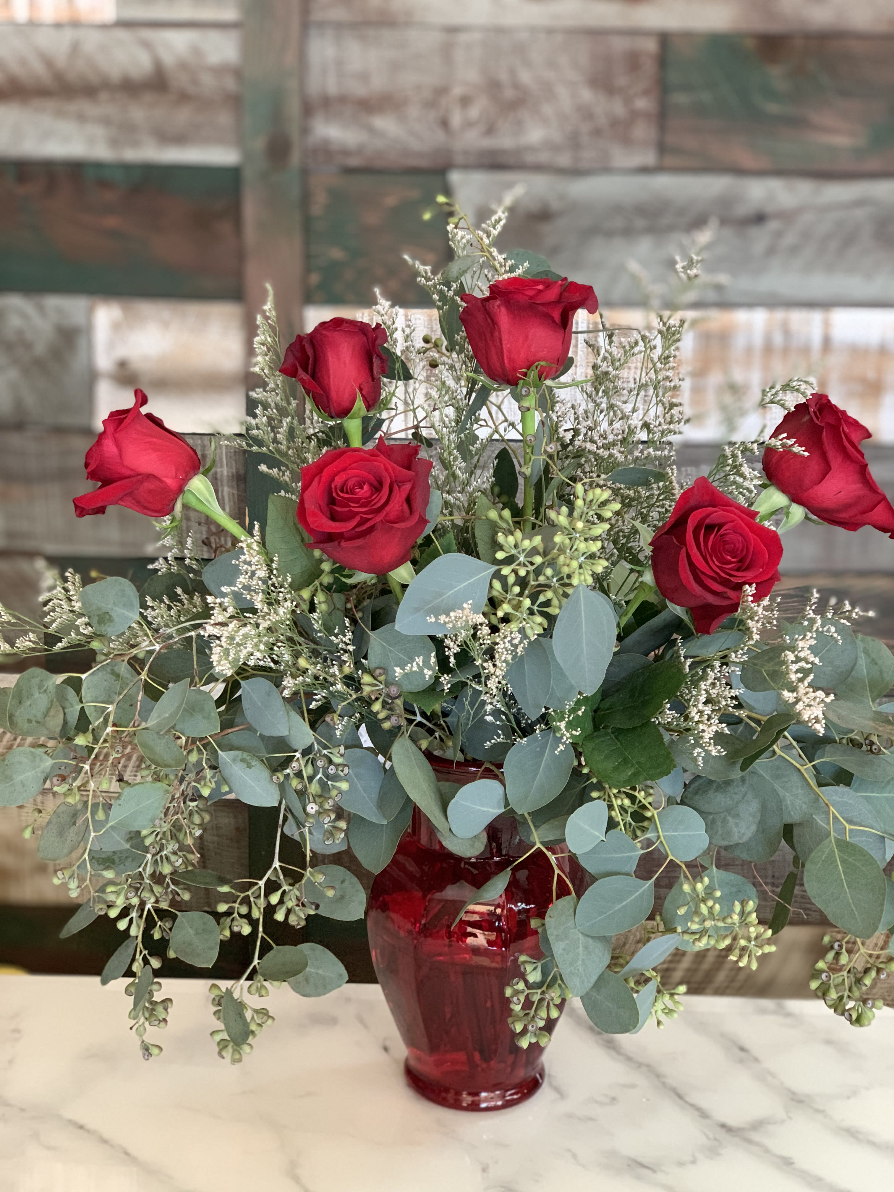 Amore - A red vase with 6 roses , eucalyptus and filler. Traditional and simple sure to make someone smile!