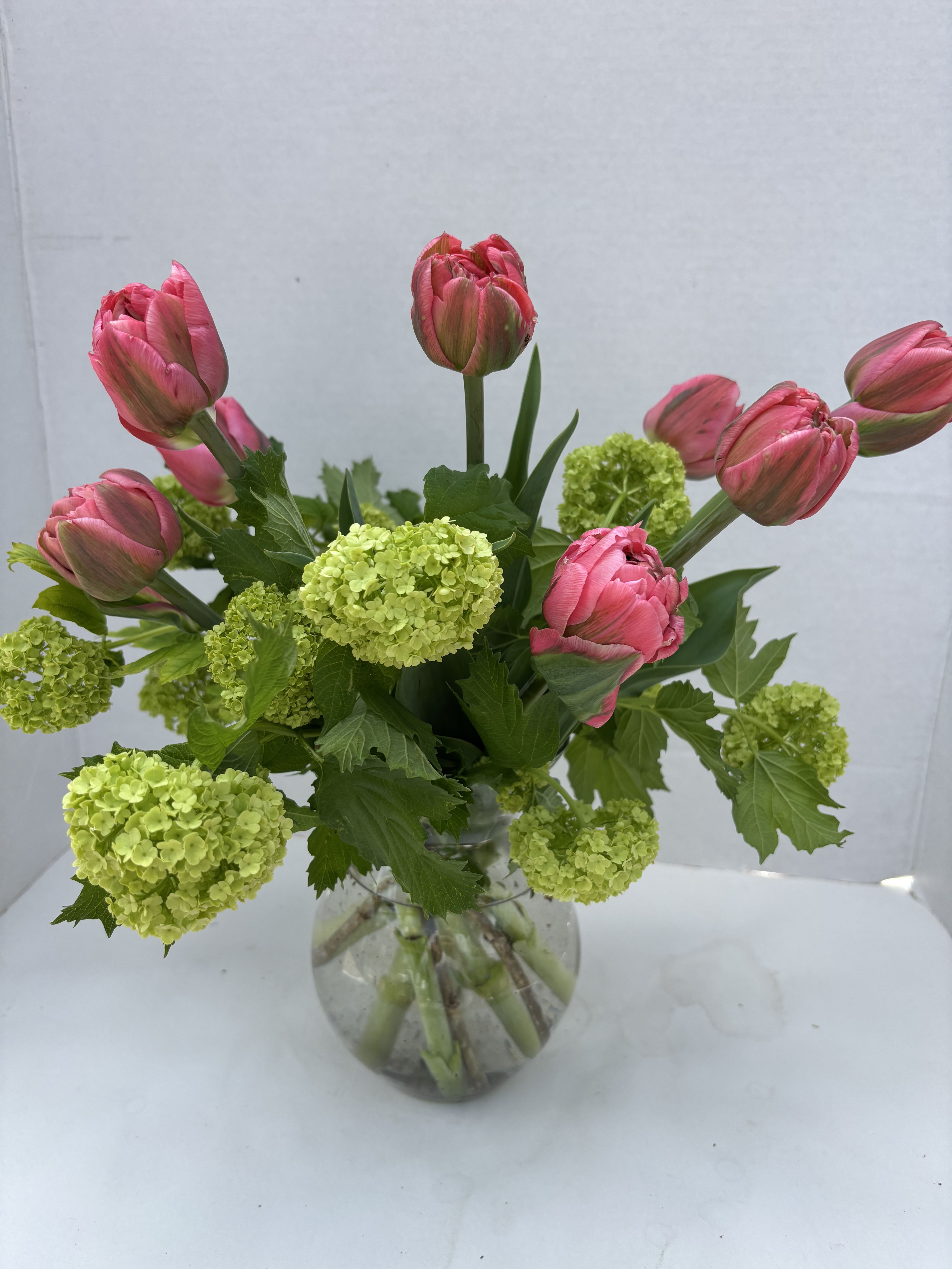 Mugfords Tulip delight - Featuring our  own  double blooming tulips and viburnum arranged in a glass vase . * tulip colors will vary depending on what is blooming