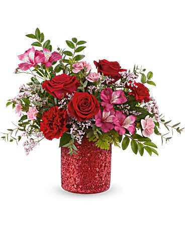 Be Dazzled Bouquet - Light up any celebration with the Be Dazzled Bouquet! Radiant red and pink blooms burst with color in a sparkling red vase, creating a joyful and unforgettable statement of beauty. Bouquet features red roses, red carnations, pink alstroemeria, miniature pink carnations, and pink limonium, accented with huckleberry, parvifolia eucalyptus, and leatherleaf fern. Presented in the Magical Wish Cylinder, a red sparkle vase. Approximately 13" W x 12" H 
