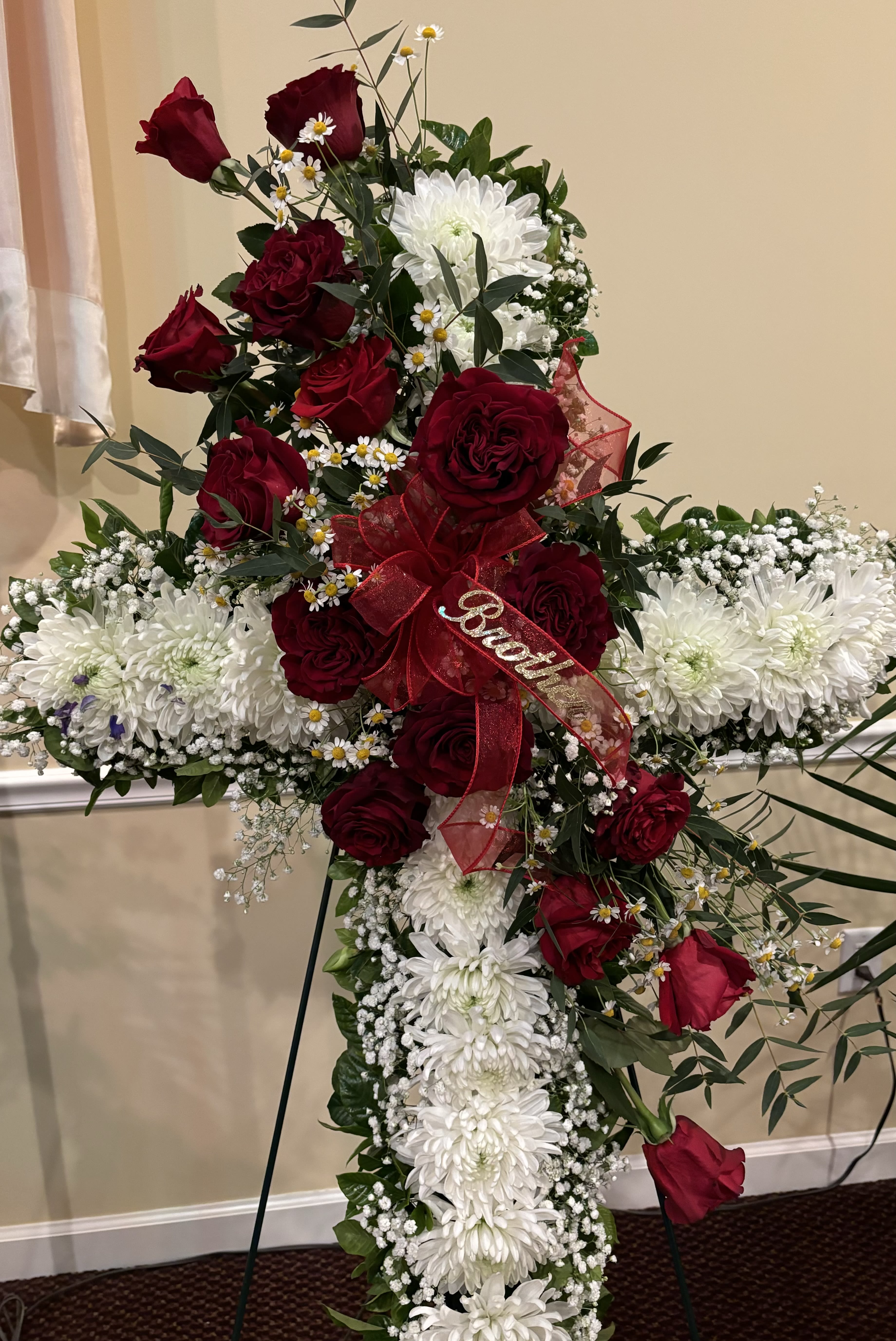 The Faithful Departed - A cross made with all white cremons and babies breath with an overlay of red roses, greens and filler