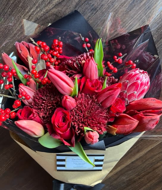 Bold Love - Send some love and cheer with this bold red bouquet of seasonal blooms.  Roses, Amaryllis, Protea, Tulips and mums make up this elegant bunch ready to create smiles any recipient. 