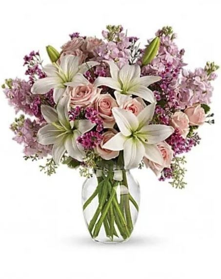 Blossoming Romance - Love is in the air. Or if it isn't, it will be when you surprise her with a gorgeous array of light pink spray roses, fragrant white lilies and other favorites in a sparkling glass vase. You know when she'll love it the most? When it's a total surprise. This lovely bouquet includes light pink spray roses, white asiatic lilies, lavender stock and lavender waxflower accented with assorted greenery. Delivered in a glass rose vase. 