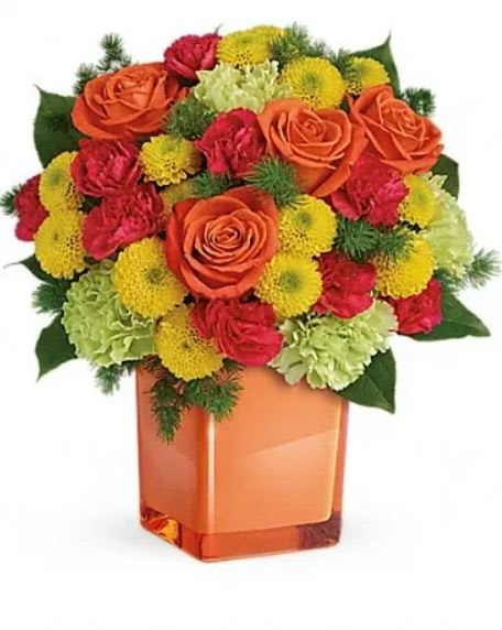 Citrus Smiles Bouquet - They brighten your days with their friendship and love, brighten theirs with these bold and beautiful blooms! Hand-delivered in a stylish glass cube, a gift in and of itself - this spirited mix of roses, carnations and mums is sure to make them smile! Bold orange roses, green carnations, dark pink miniature carnations, and yellow button spray chrysanthemums are mixed with ming fern and lemon leaf. Delivered in a glass cube. 
