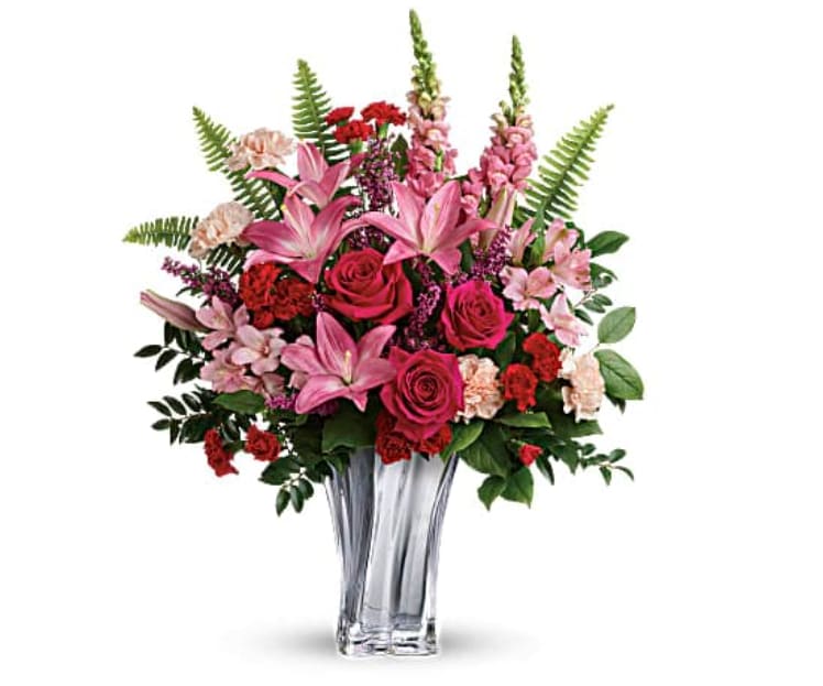 Elegant Adoration Bouquet 1 - At once elegant and romantic, this breathtaking red and pink bouquet features luxurious blooms and an equally luxurious vase of blown, sterling silver mirrored glass with sleek swirling lines. This elegant bouquet includes hot pink roses, pink asiatic lilies, light pink alstroemeria, peach carnations, red miniature carnations, pink snapdragons, pink heather, sword fern, huckleberry, and lemon leaf. Delivered in a Sterling Love Vase.