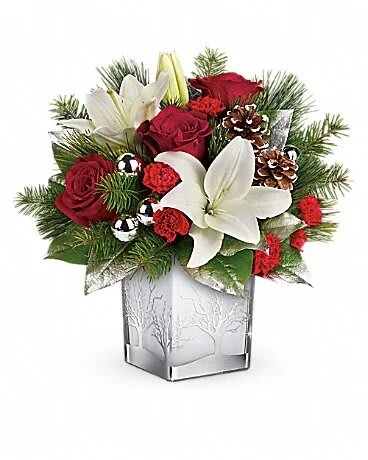 Frosted Forest Bouquet - With its festive charm and classic Christmas style, this hand-arranged bouquet delivered in a gorgeous glass cube with silver tree details is a delightful holiday surprise. Red roses, white asiatic lilies and red miniature carnations are accented with douglas fir, white pine, and lemon leaf. Delivered in a Woodland Winter cube.