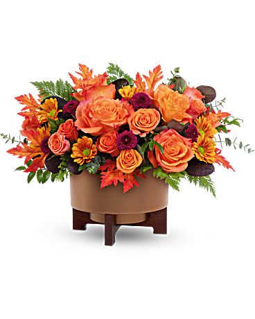 Fall For Copper Centerpiece - Turn up the autumn glow with Teleflora's Fall For Copper Centerpiece. Bursting with vibrant orange blooms and rich fall foliage in a modern copper-finished planter, this centerpiece is a warm and stylish way to celebrate the season Teleflora's Fall For Copper Centerpiece is arranged in Teleflora's Modern Copper Planter with wooden stand. It features orange roses, orange spray roses, bronze daisy spray chrysanthemums, and purple button spray chrysanthemums. Accents include cotinus, spiral eucalyptus, huckleberry, and leatherleaf fern Orientation: All-Around  SUBSTITUTION POLICY – Always deliver the freshest flowers! Please note the bouquet pictured reflects our original design.  If the exact flowers or container in this arrangement are not available, our local florists will create a beautiful bouquet with the freshest available flowers.