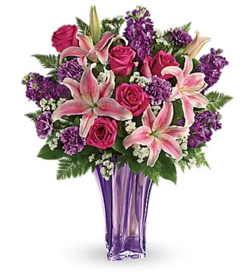Luxurious Lavender Bouquet - "The essence of luxury! This dramatic bouquet spoils her with a decadent array of luxe lilies and resplendent roses, hand-delivered in a stunning blown glass vase that's a grand gift in and of itself. Fabulous! This arrangement includes pink roses, pink oriental lilies, purple carnations, white sinuata statice, leatherleaf fern, and lemon leaf. Delivered in a Luxurious Lavender vase.   Orientation : One-Sided  All prices in USD ($)  Standard  TEV49-1A  Deluxe  TEV49-1B  Premium  TEV49-1C"