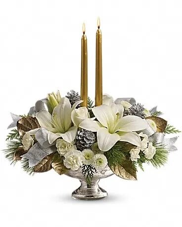 Silver And Gold Centerpiece - Inspired by the magic of the first snow, this elegant centerpiece of pure white lilies and winter greens, arranged in a stunning mercury glass bowl makes a fresh, fragrant addition to your holiday table, or a breathtaking gift for someone special. This stunning arrangement includes white roses, white asiatic lilies, white miniature carnations, white button chrysanthemums, flat cedar, white pine and lemon leaf, accented with small silver pinecones, gold taper candles and silver ribbon. Delivered in an exclusive Mercury Glass bowl.