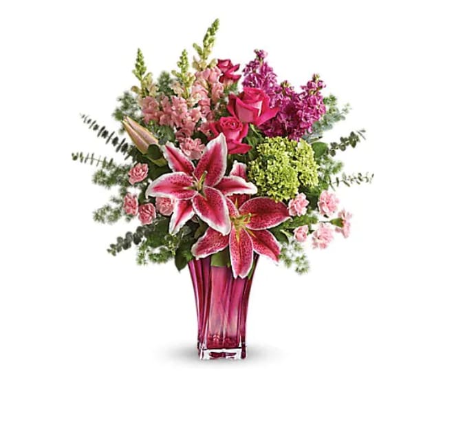 Steal The Spotlight Bouquet - When spoiling mom is the name of the game - steal the spotlight with this magnificent arrangement! Hand-delivered in a glorious glass blown vase, this luxe Mother's Day bouquet of fragrant lilies, roses, snapdragons and hydrangea will truly take her breath away. Pink stargazer lilies, pink snapdragons, pink stock, hot pink roses, green miniature hydrangea, and pink miniature carnations are accented with lemon leaf, ming fern, and spiral eucalyptus. Delivered in a Bold Elegance vase.