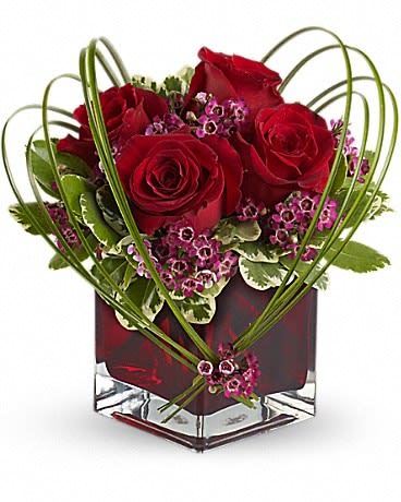Sweet Thoughts Bouquet with Red Roses - If you'd like someone to think sweet thoughts about you, send them this delightful bouquet! A graceful heart of bear grass is tied with purple waxflower, and appears to float above red roses nestled in a ruby-red glass vase. How sweet it is! Red roses and purple waxflower accented with variegated pittosporum and bear grass arrive in a Teleflora red glass cube vase. 