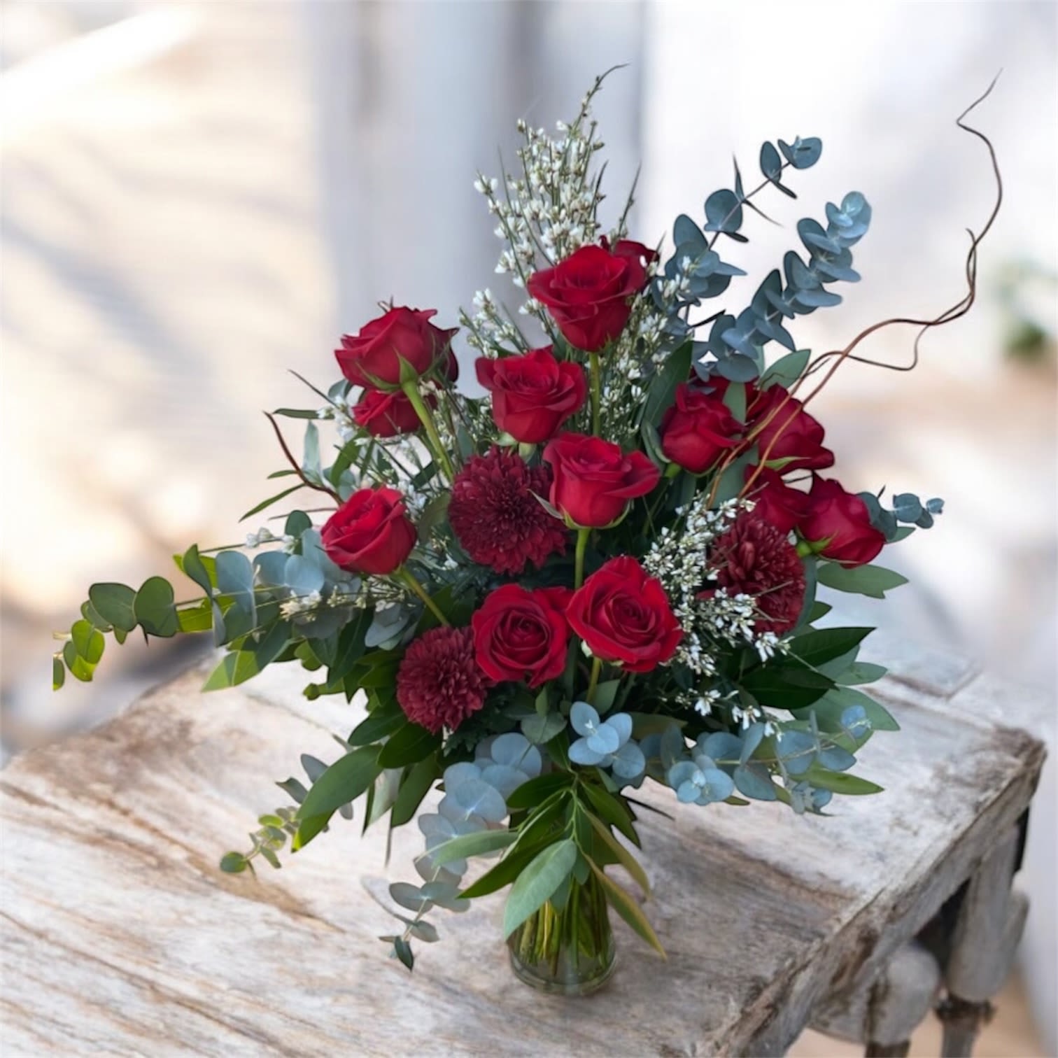 Whimsy Red  - A fun whimsical red rose arrangement perfect for Valentine’s Day.  One dozen roses with red mum accents and fresh eucalyptus cut right out of our garden.  