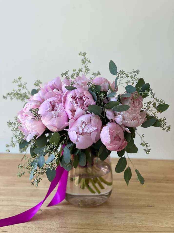 Peony Dans L'eau - "Peony Dans L'eau", is an arrangement with twelve of our most gorgeous peonies, sourced from the Mountains of Patagonia. Designed beautifully in a glass cylinder vase along with seeded eucalyptus &amp; topped off with a silk ribbon.