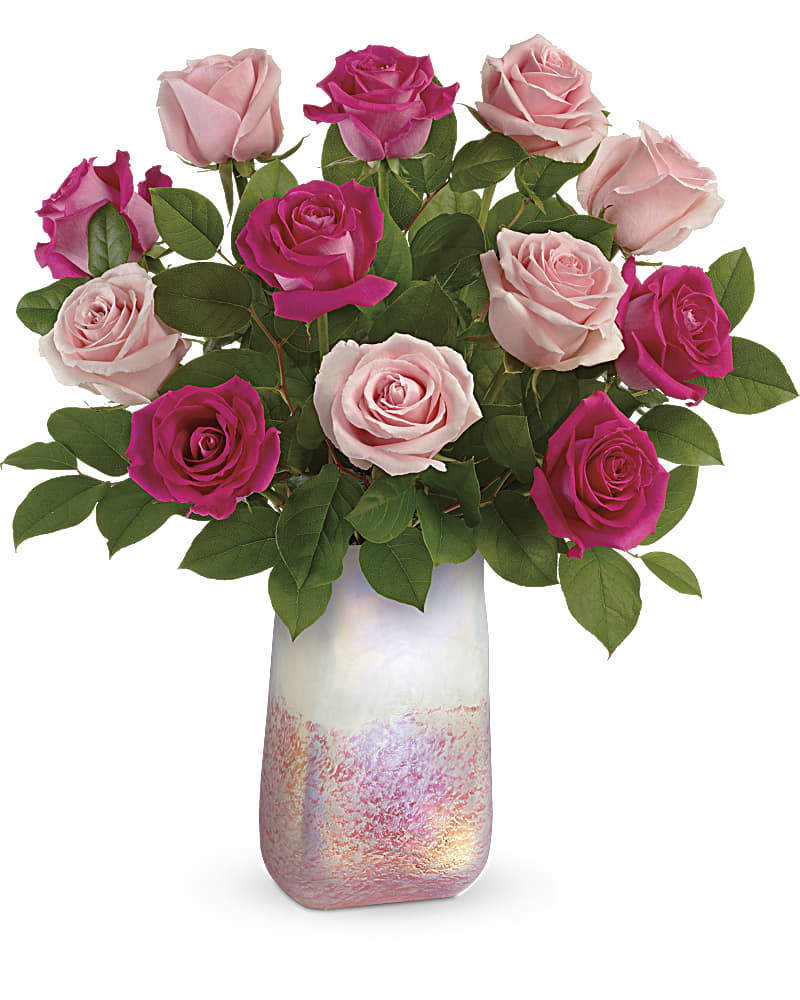 Rose Quartz Kisses Bouquet - Make them swoon this Valentine's Day! One dozen lush pink roses are just the thing, especially when accompanied by this amazing iridescent, hand-blown art glass vase. 6 hot pink roses and 6 light pink roses are arranged with lemon leaf. Delivered in  in Rose Quartz vase. Standard- 12 Roses Deluxe- 18 Roses Premium- 24 Roses 