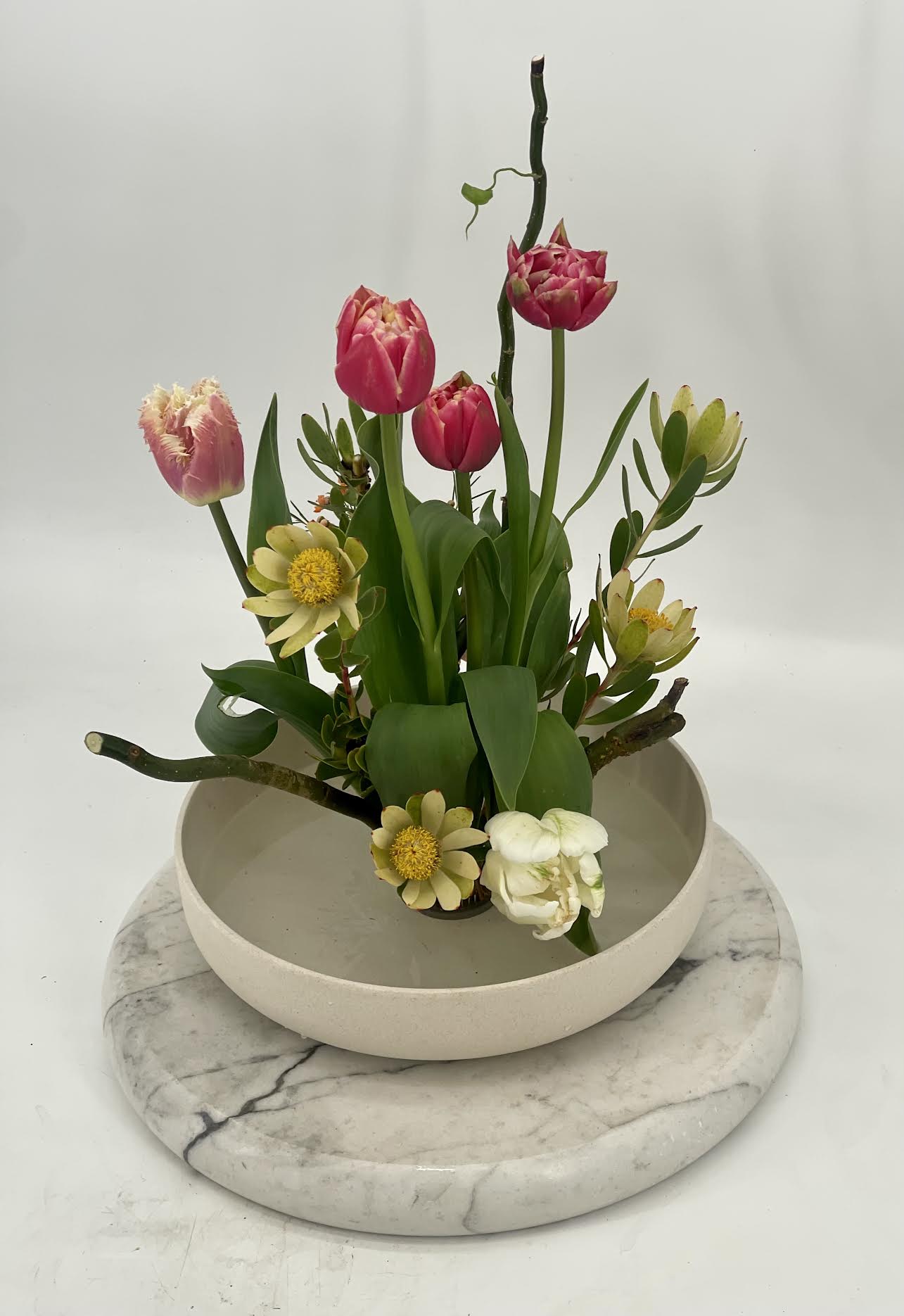 Ikebana Essence  - A refined Ikebana -style arrangement inspired by Japanese artistry .Sculptural blooms and natural elements are thoughtfully placed to created  balance ,movement ,and elegance in a minimalist vessel.