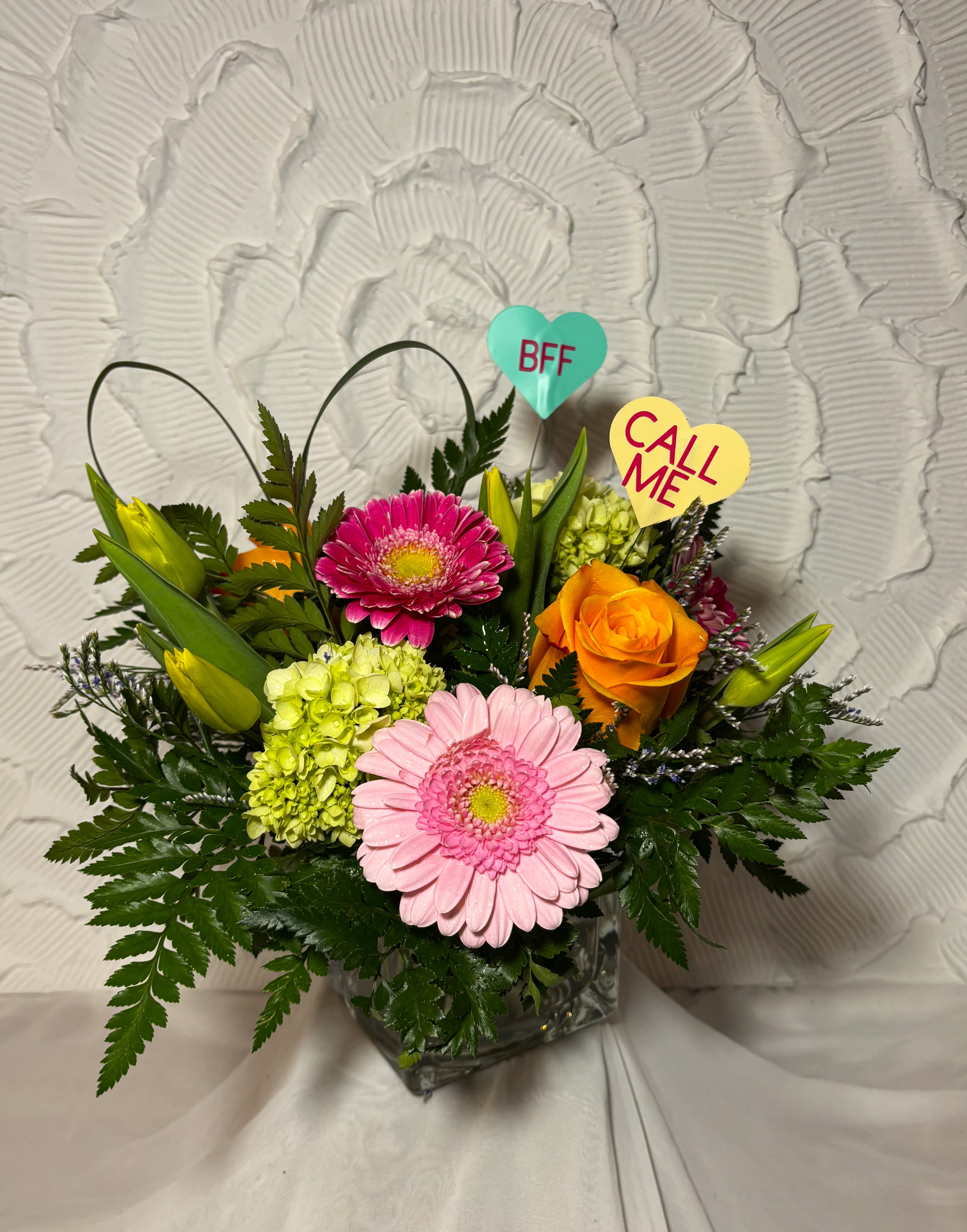 Something Sweet - This vase is made of, yellow tulips, orange roses, light and dark pink gerbera daisies, limonium and two little hearts to pull it all together. This is the perfect vase for you if your looking for something sweet.