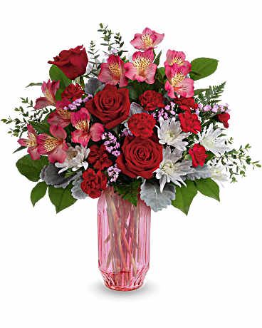 Gorgeous Gem Bouquet - Celebrate love's radiant hues with the Gorgeous Gem Bouquet, a stunning Valentine's Day mix of red and pink blooms in a shimmering faceted pink glass vase that sparkles with modern romance. Bouquet includes red roses, pink alstroemeria, red miniature carnations, white cushion spray chrysanthemums, pink sinuata statice, dusty miller, parvifolia eucalyptus, leatherleaf fern, and lemon leaf in the Gorgeous Gem Vase. Approximately 17 3/4" W x 18 1/2" H