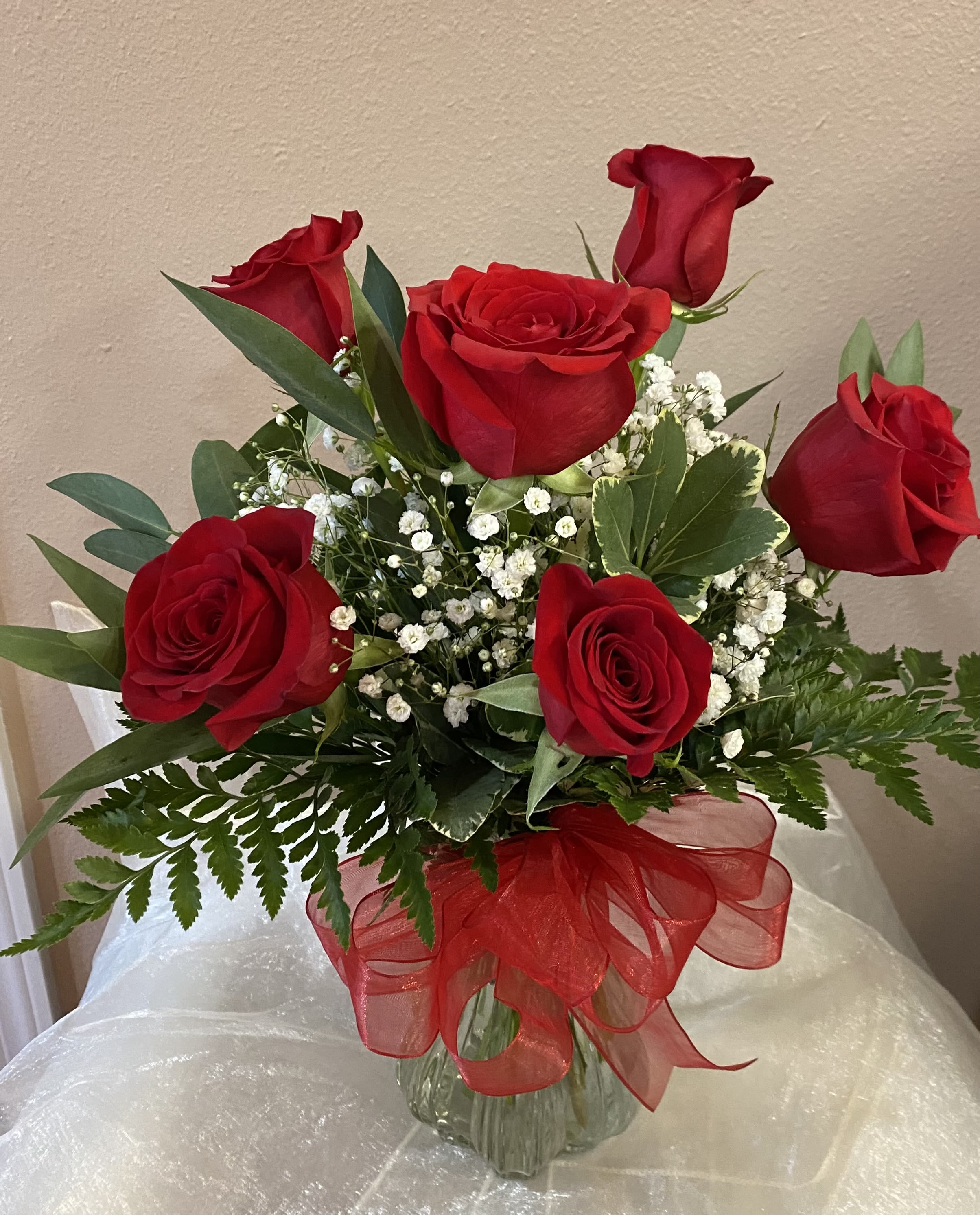 Half Dozen Red Roses - Six classic red roses accented with filler and greens, beautifully arranged with a bow to finish it off. A timeless choice for love, romance, or any heartfelt occasion.