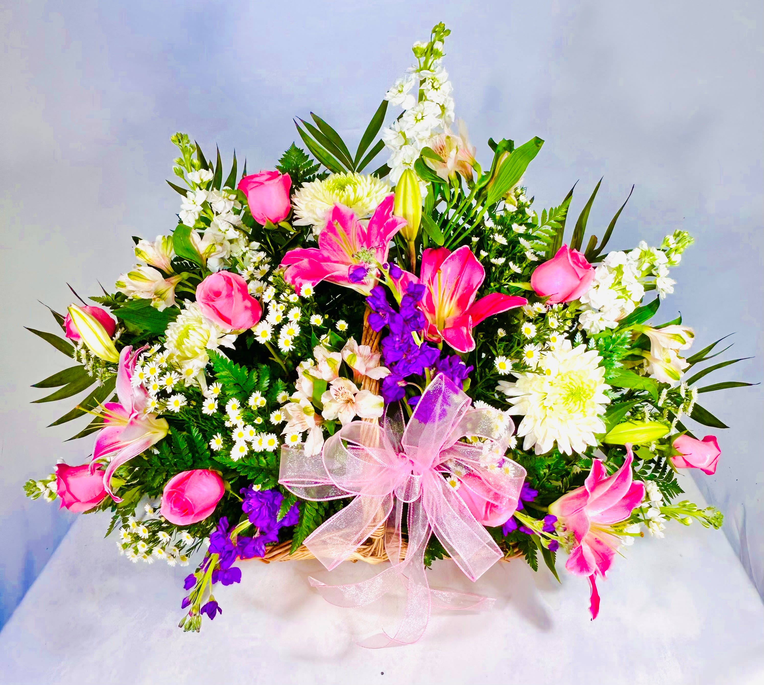 Sincerest Sympathies Basket - This beautiful basket has an abundant supply of gorgeous pink lilies, pink roses, white and purple stock, white monte casino and pink alstroemeria with a beautiful pale pink bow. Express your deepest sympathies with this basket that makes a touching tribute. 